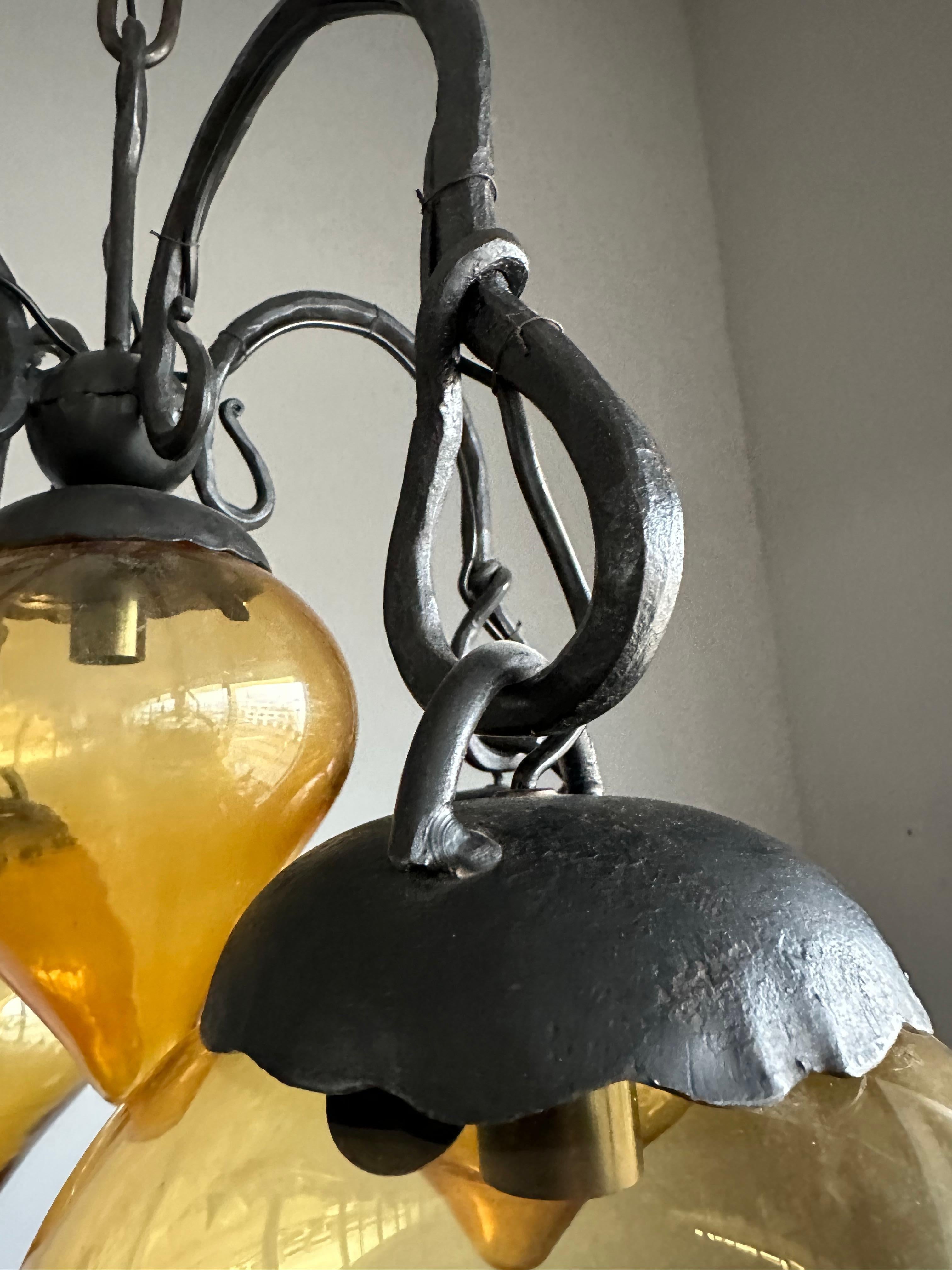 Verre brun Lustre en fer forgé du milieu du siècle, forgé à la main, avec. Cinq abat-jour en verre soufflé ambré en vente