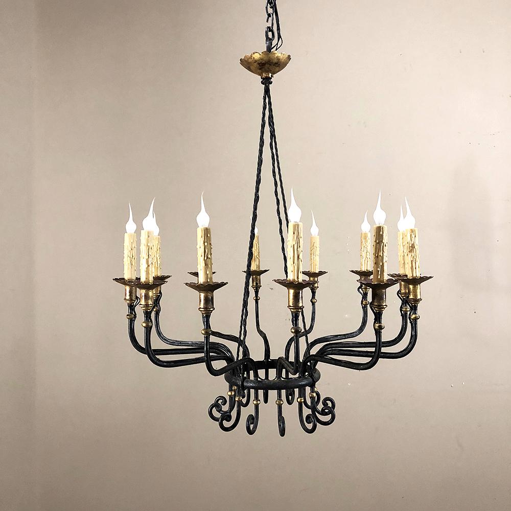 Midcentury hand forged wrought iron country French chandelier with gold painted accents features a delightfully airy midcentury design, accented by bronze ferrules and a copper canopy above with bronze bobeches under each chandelle. Meticulously
