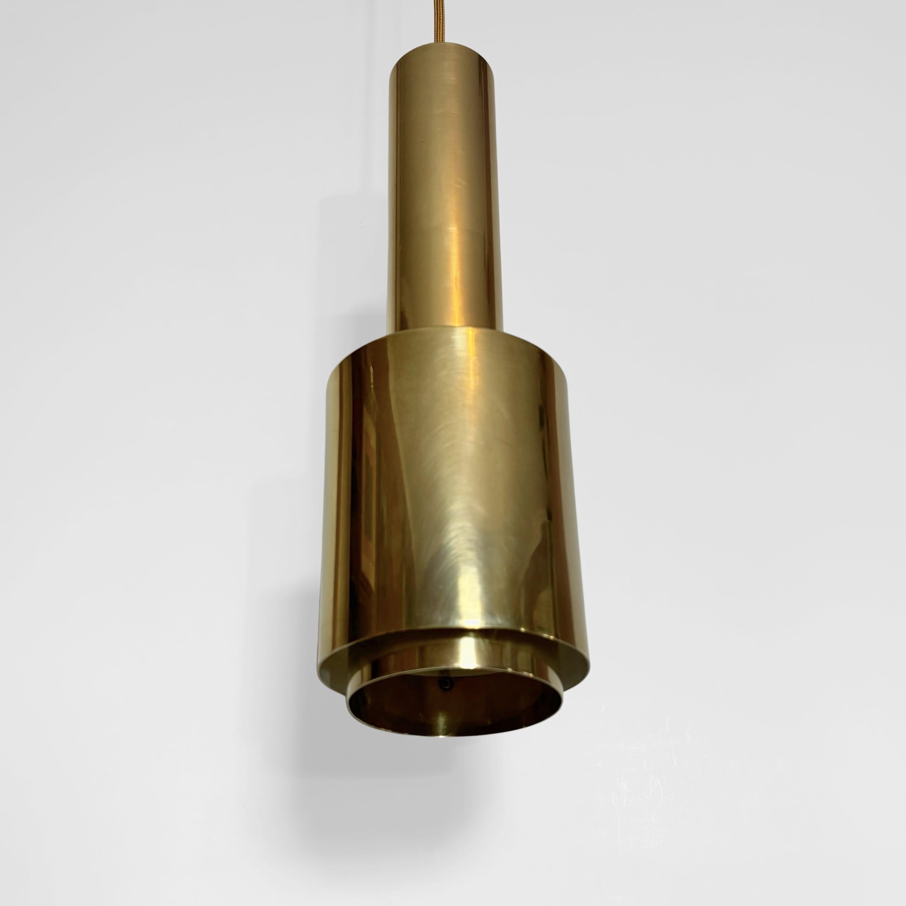 Una lampada a sospensione di metà secolo alla maniera di Alvar Aalto, a forma di bomba a mano. Realizzato in ottone massiccio con una meravigliosa patina dovuta all'età. L'apparecchio è composto da un tubo superiore, un cilindro più grande e un