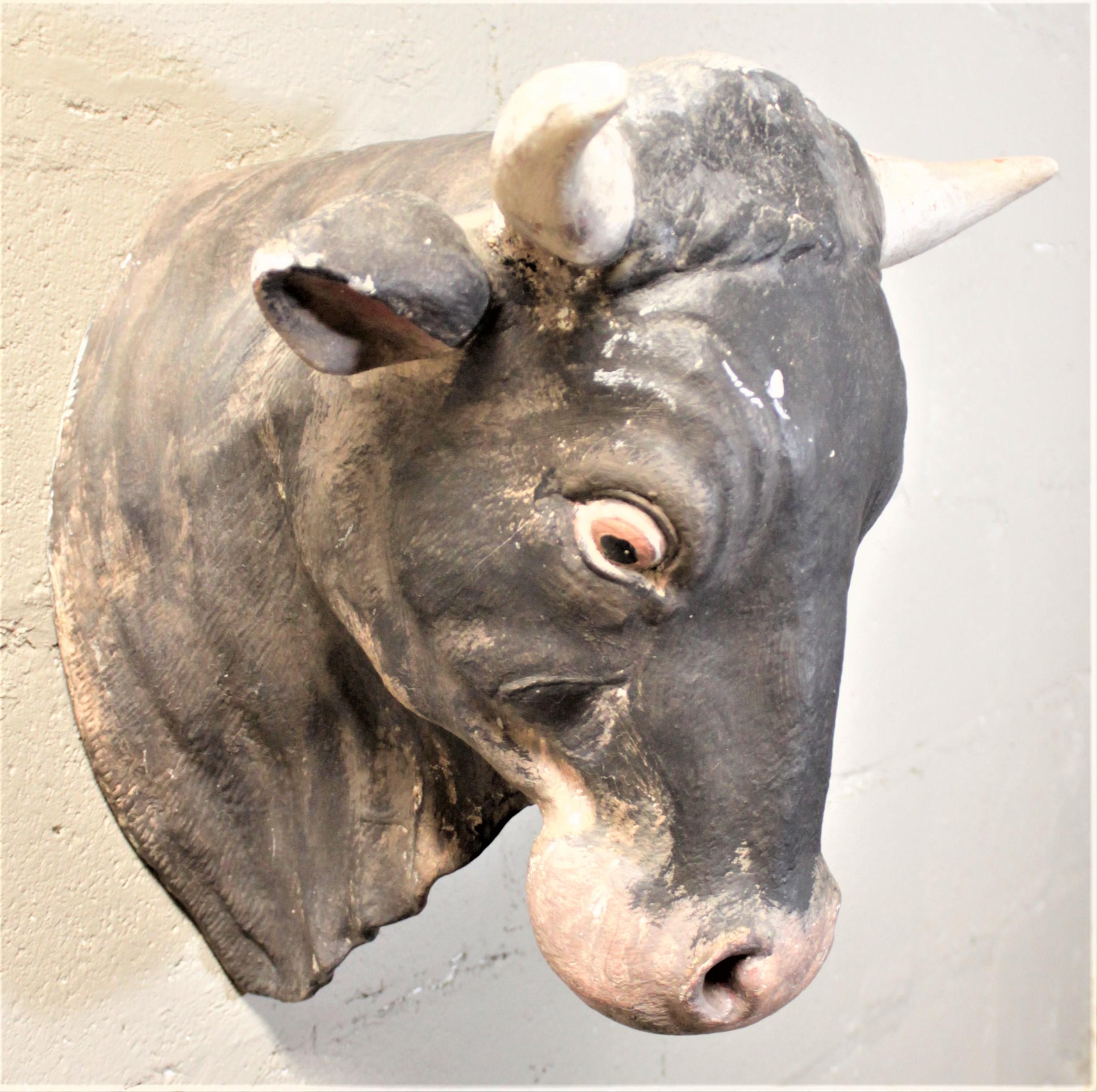 This 1960s era molded fiberglass and hand painted bull's head is unsigned, but believed to be a generic advertising wall decoration from a butcher shop. This head is hand painted in a whimsical Folk Art style and uses muted tones.