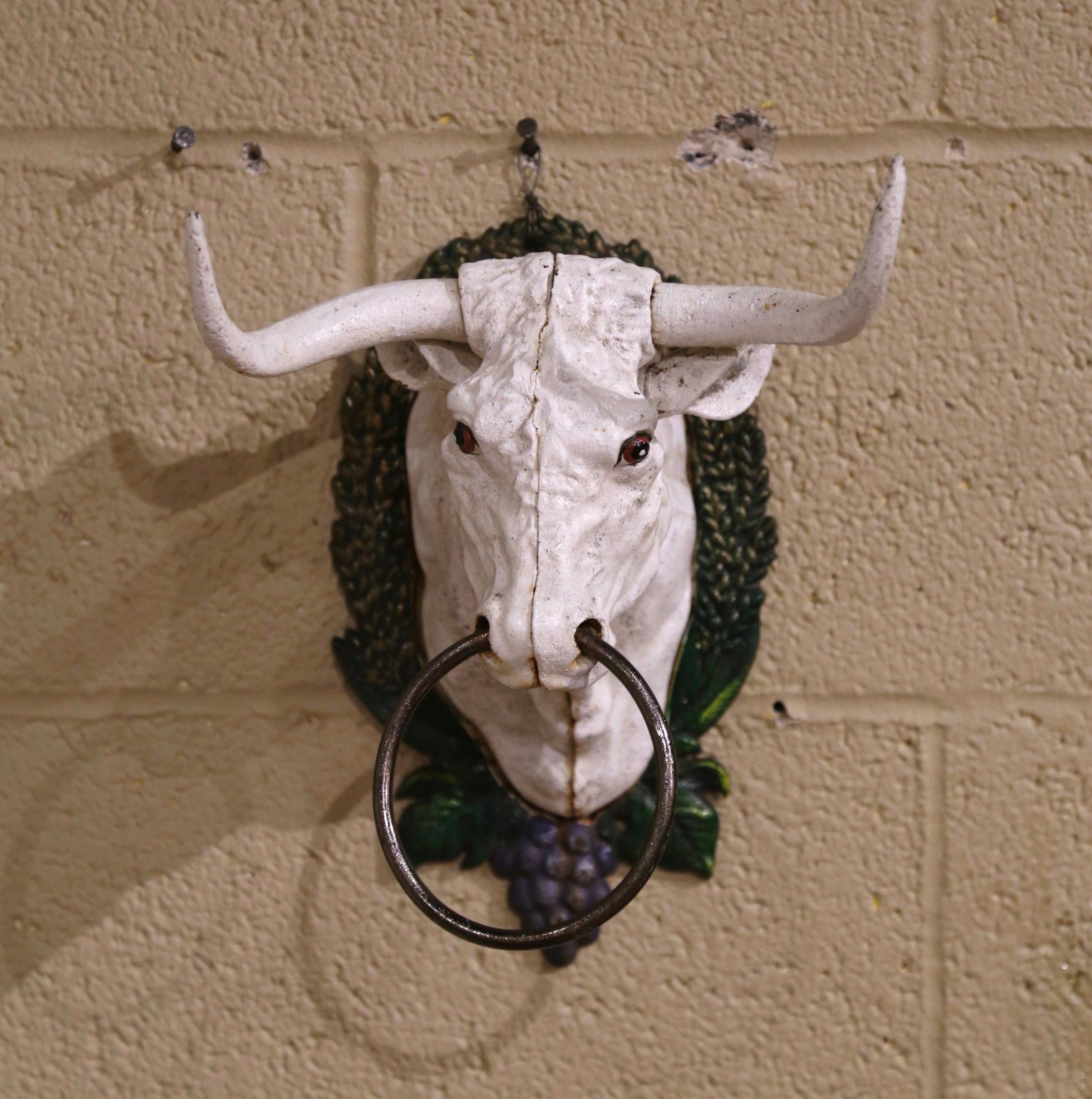 This beautiful cow head bust was crafted in France circa 1960. The hand carved sculpture made of iron, features a realistic bull head with two large horns and a metal ring through the nostrils, is surrounded by a foliage border with grape decor