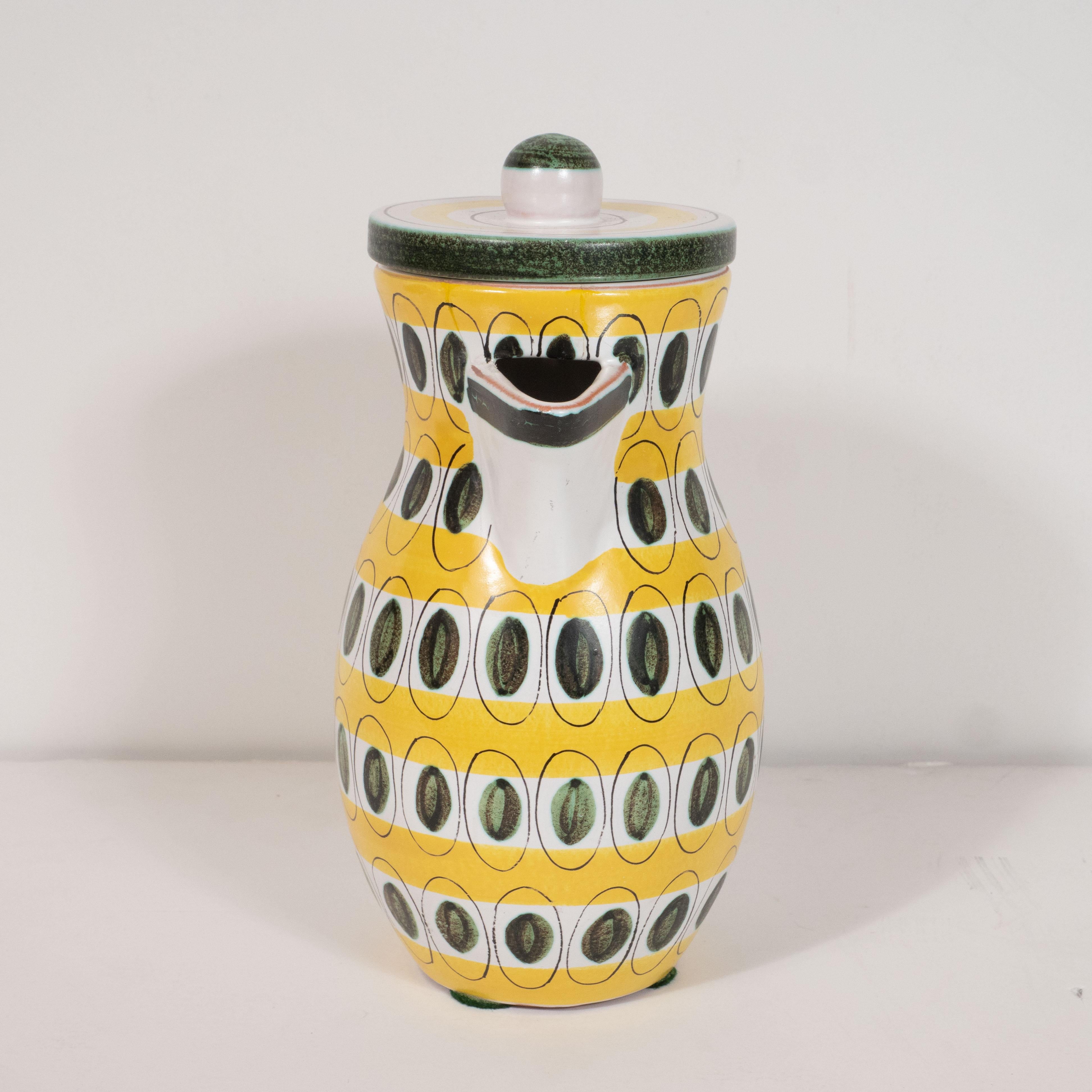 This fun and sophisticated pitcher was realized by the celebrated pottery studio Stig Lindberg in Sweden, circa 1960. It features a white undulating body hand painted with sunflower yellow bands and ovoid hunter green dots (resembling martini
