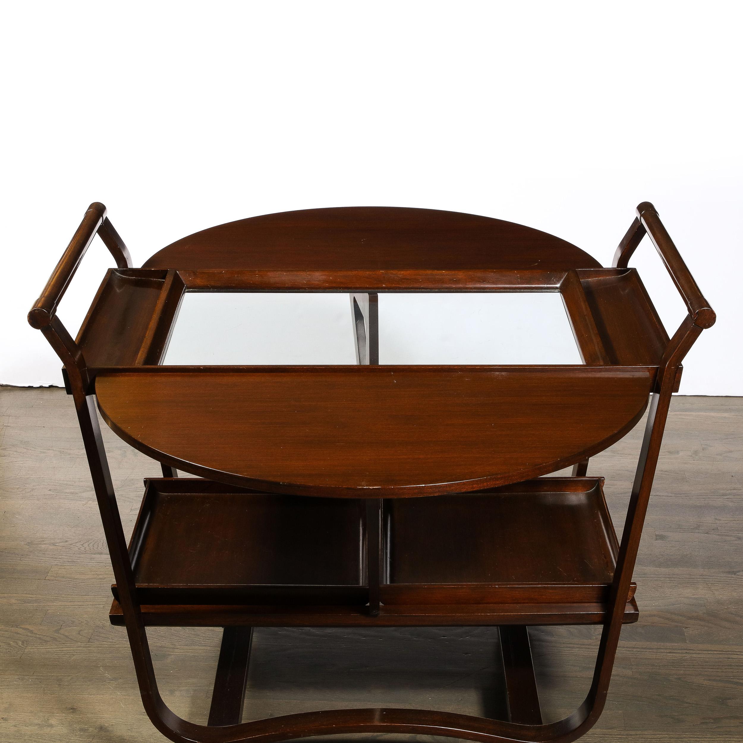 This Mid-Century Modernist Walnut Drop Leaf Bar Cart was created by the illustrious designer Edward Wormley for Dunbar originating from the United States, Circa 1950. Featuring a lovely combination of bent wood framework and simplified geometric
