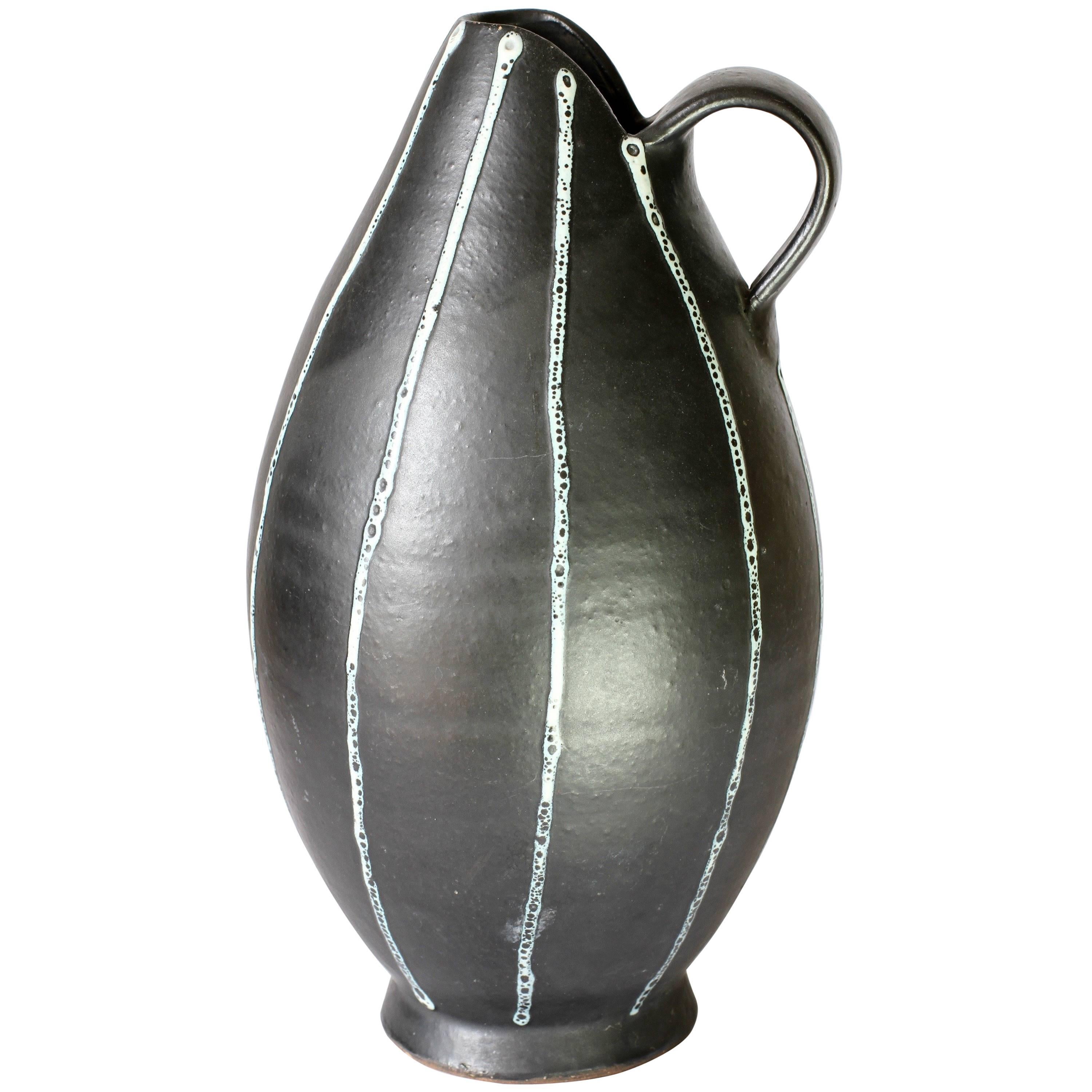 Elegant jug or pitcher, hand thrown by an unknown studio potter, circa 1950-1959. It is certainly of European origin and most likely German made as it has very similar glaze techniques to those found on vases from the West German Pottery companies