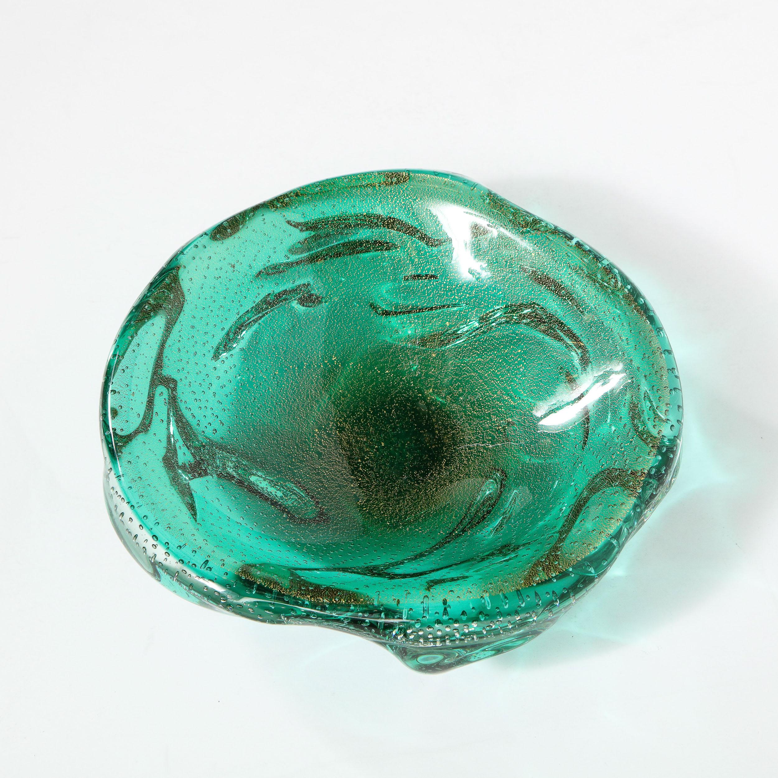 This elegant Mid-Century Modern bowl was realized in Italy, circa 1950. It features a sculptural silhouette composed of hand blown Murano glass in a rich sea foam teal hue with translucent murines and 24-karat yellow gold flecks throughout. With its