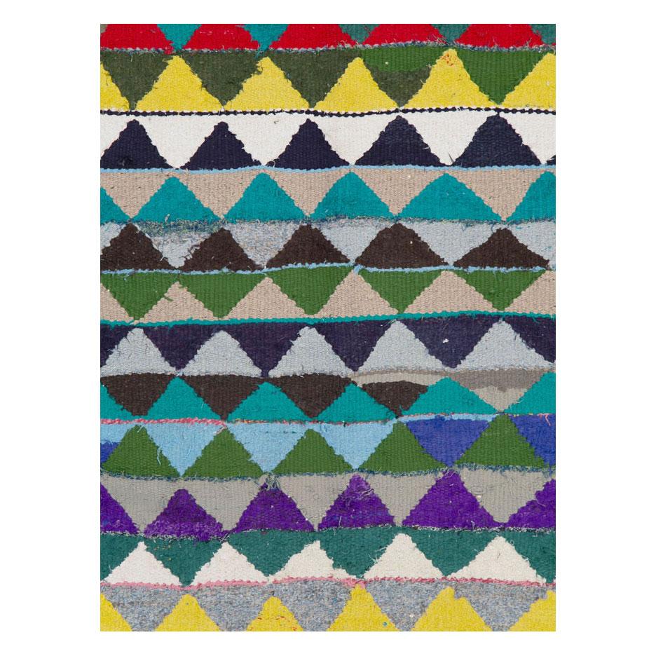 A colorful vintage Persian 5' x 7' flat-woven kilim rug handmade during the mid-20th century consisting of endless triangles in shades of blue, green, red, yellow, teal, turquoise, beige, grey, purple, and brown.

Measures: 5' 2
