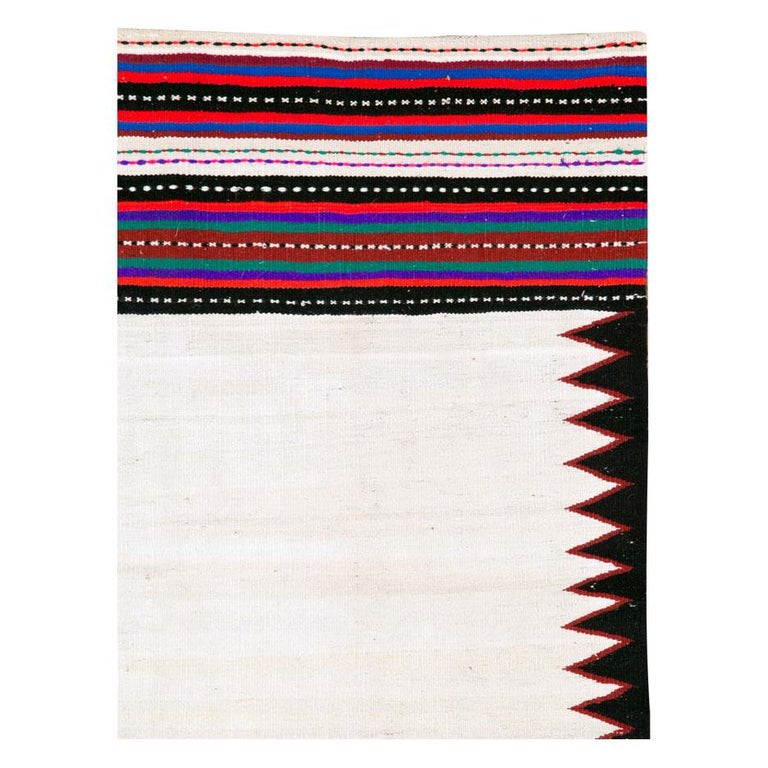 A vintage Persian tribal flat-weave Kilim rug handmade during the mid-20th century with an ivory-white field with black serrated triangles to the side. The end borders showcase more colors including red, green, purple and pink.