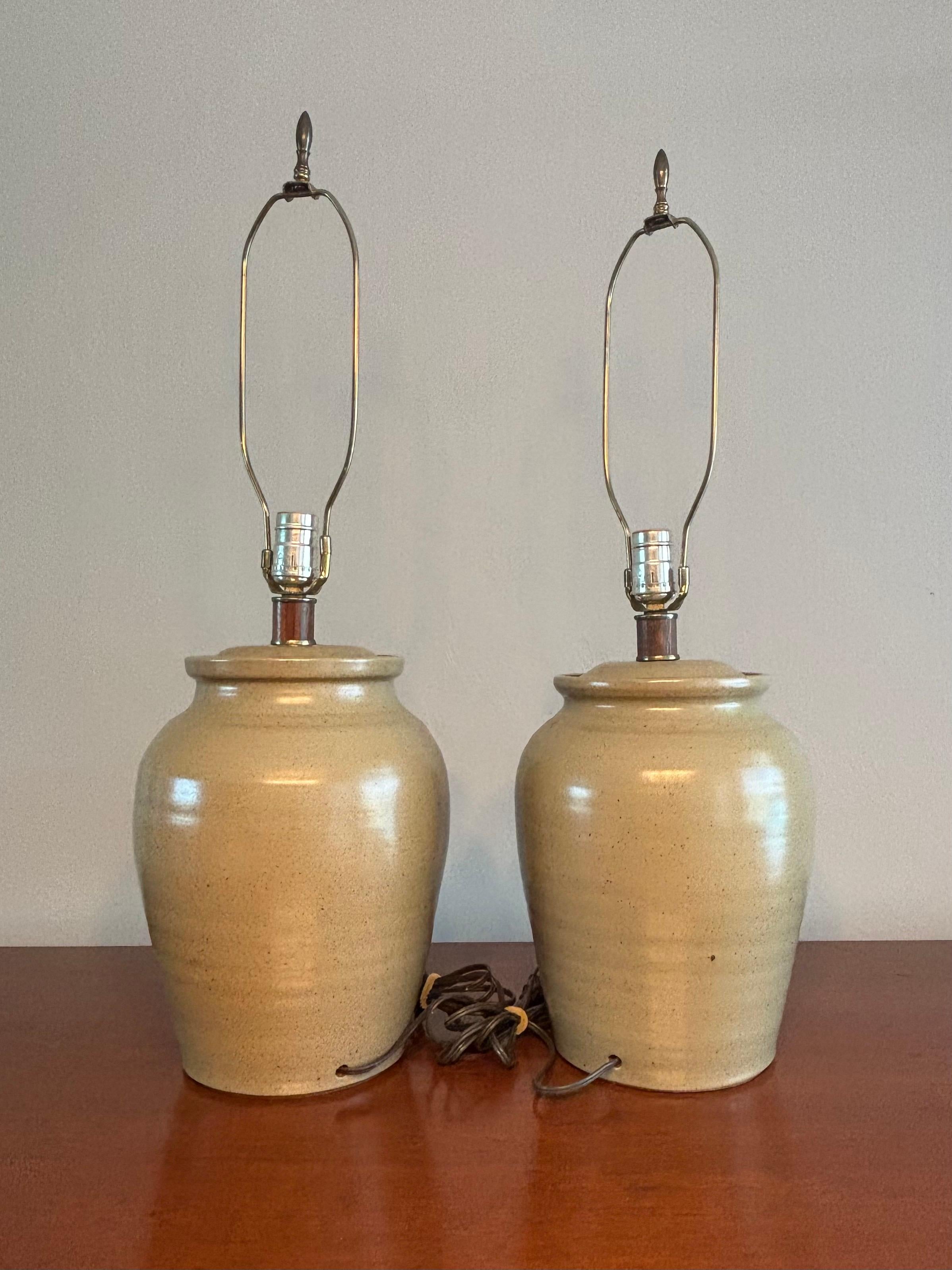 Exceptional pair of hand thrown studio ceramic lamps. A modernist take on a ginger jar shape. A beautiful natural organic olive green color glaze. 

Lamps are hand thrown and you can see the texture of it in its silhouette. The lamps are two