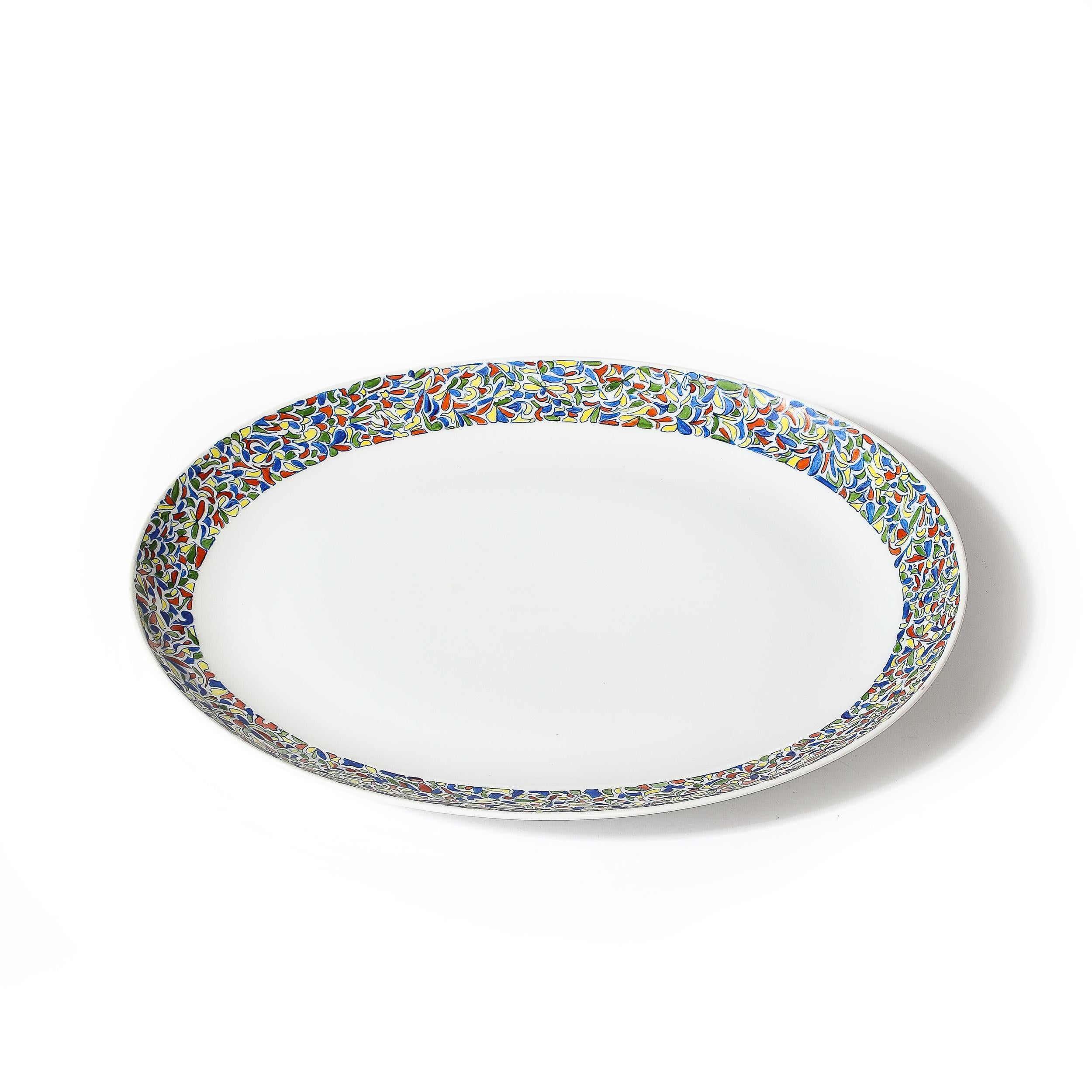 Ce magnifique plat de service en porcelaine peint à la main par Villa Vanilla Palm Beach, propriété de Pauline Trigère, est originaire des États-Unis, C.C.C. 1976. Composition ovale avec une lèvre surélevée ornée d'une bordure multicolore étonnante
