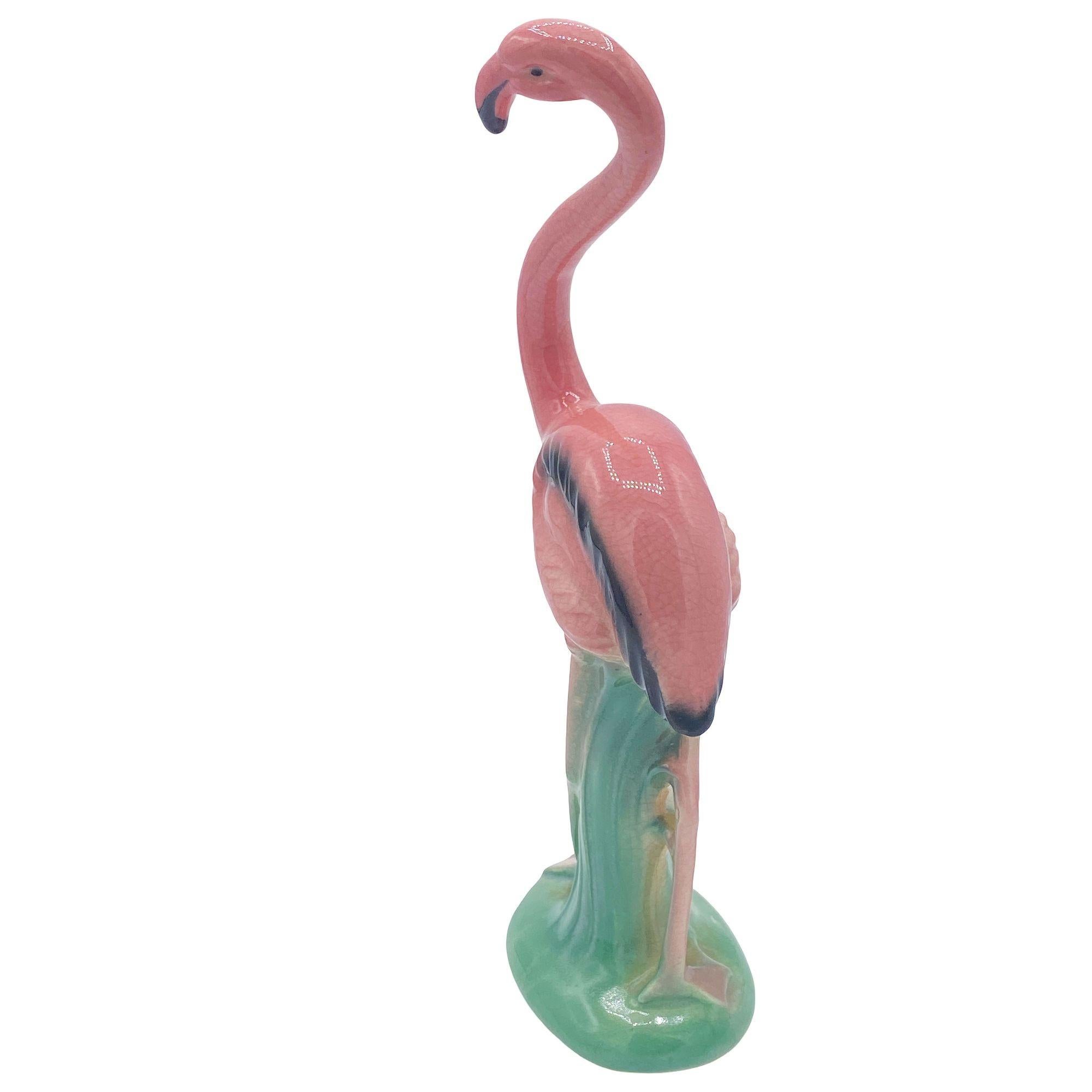Mid-century pink and green ceramic handsome flamingo tabletop pottery statue by Leftons. The statue features a beautifully detailed pink flamingo standing on a grassy field. It comes in a gloss finish that highlights the rich pinks, greens, and