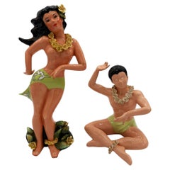 Pareja de estatuillas de cerámica de mediados de siglo, pintadas a mano, con motivos hawaianos: una chica haciendo hula y un surfista