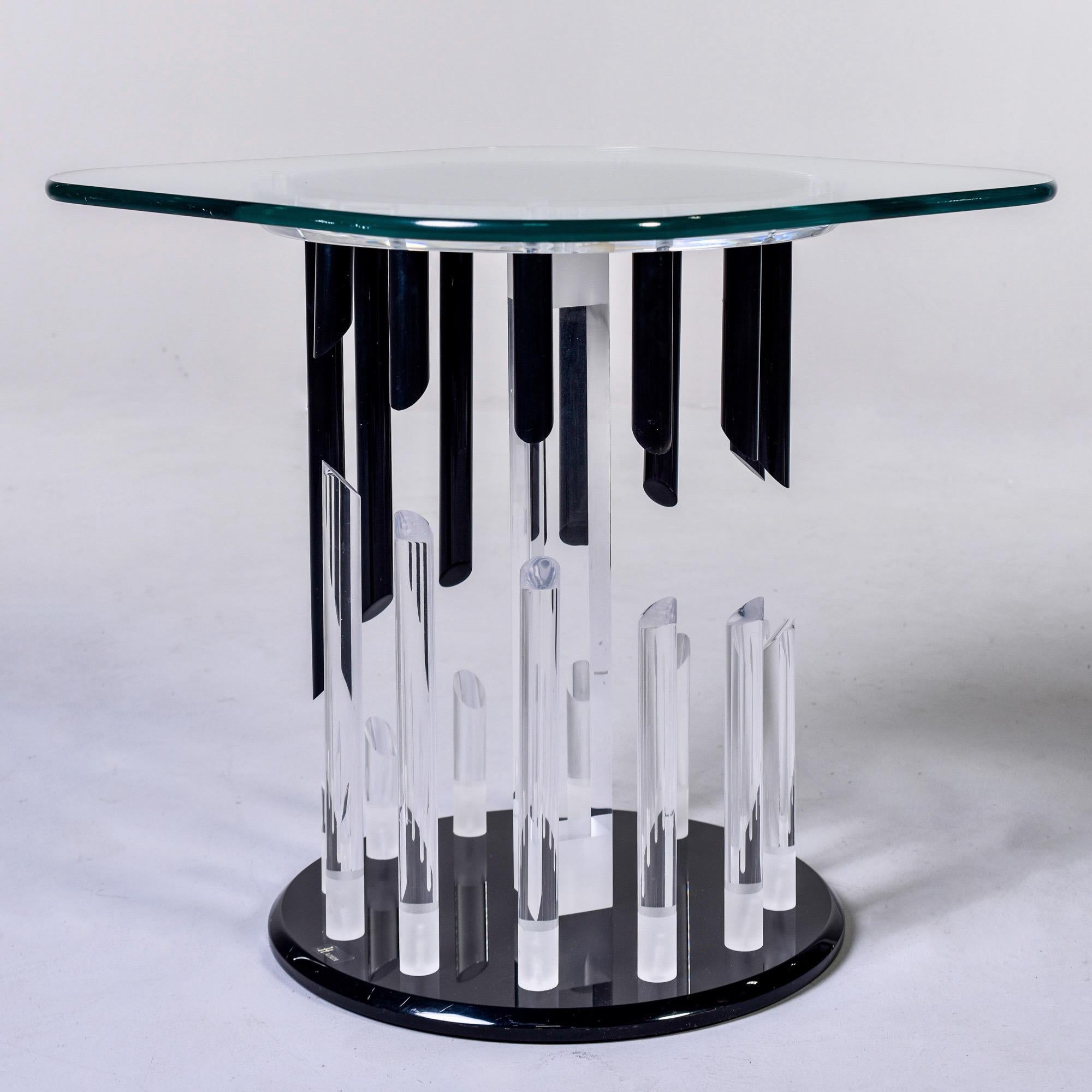 Side table with a Lucite base by Haziza, circa 1980s. Table has a black Lucite base with clear and black Lucite rods with diagonally cut ends that form an abstract pattern. Top of base is clear Lucite and tabletop is a glass square with rounded