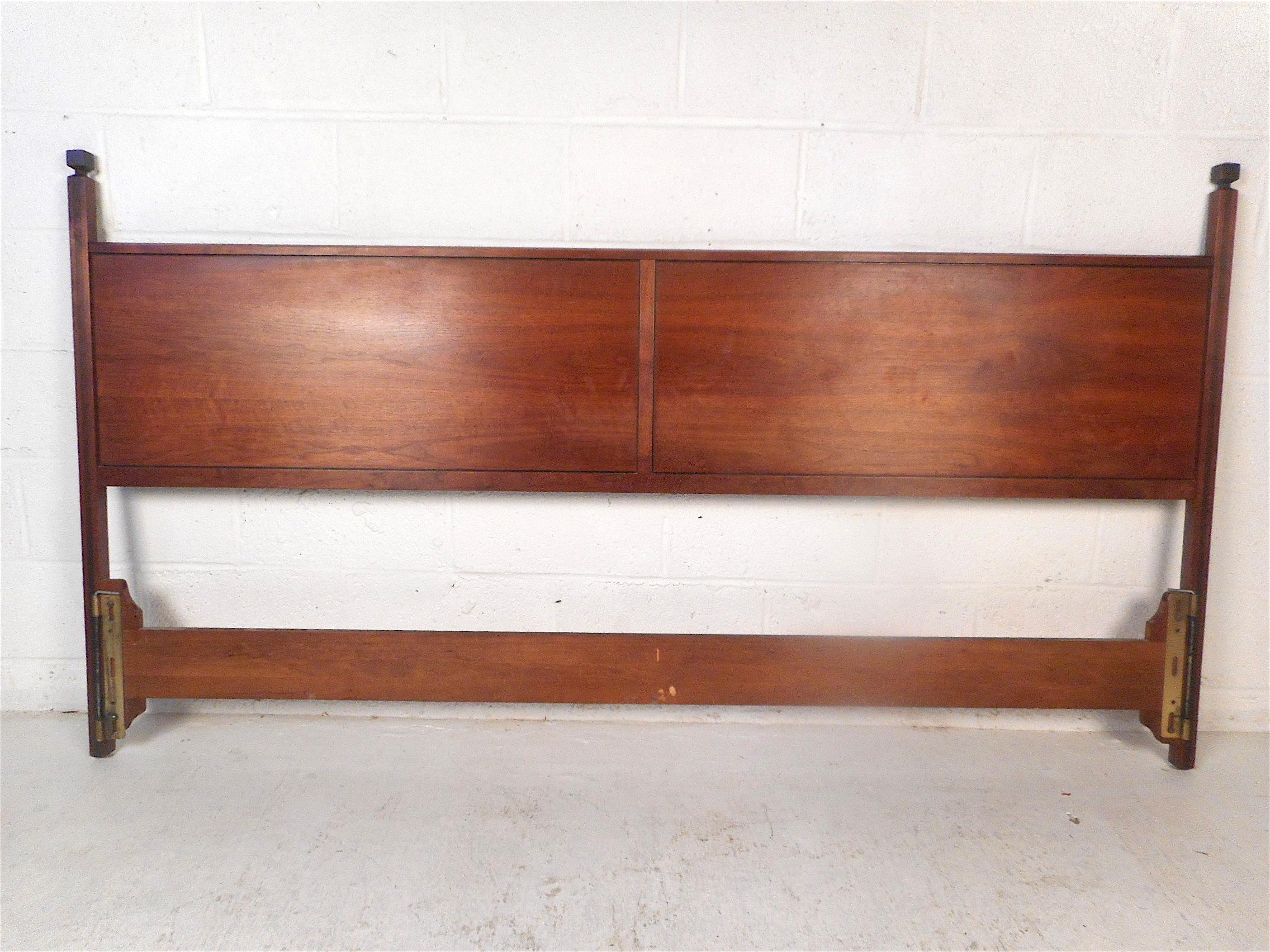 Stylish midcentury headboard. Two large panels with sleek woodgrain compose the board's body, with supports on either end featuring ornamental toppers and inlaid accents. Attributed to Paul McCobb. This headboard is sure to impress in any modern