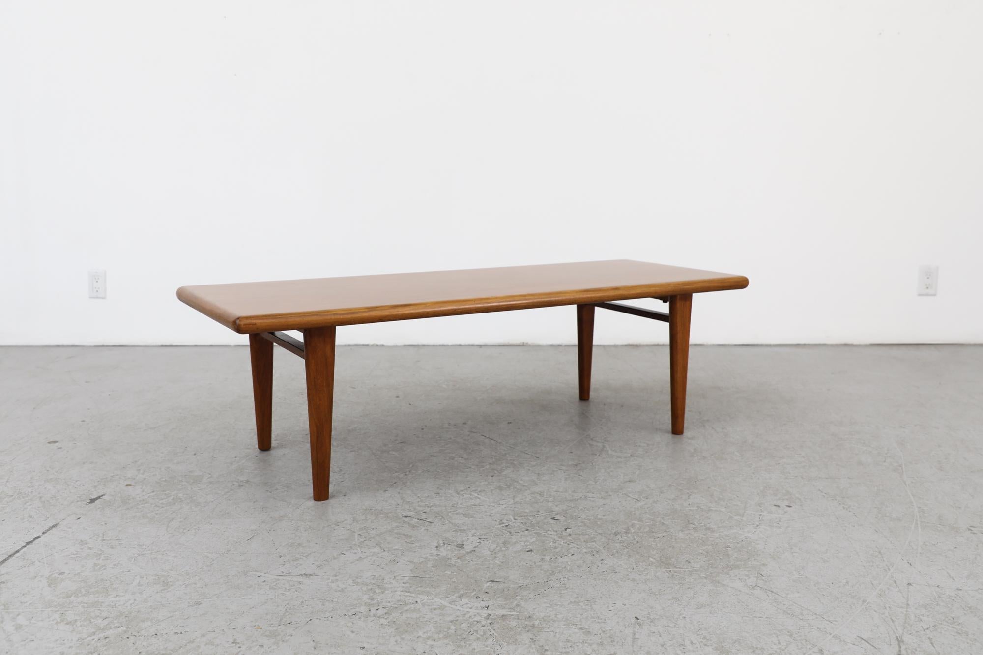 Mid-century Danish teak coffee table with thick top, rounded edges and tapered legs. In original condition with visible wear consistent with its age and use.