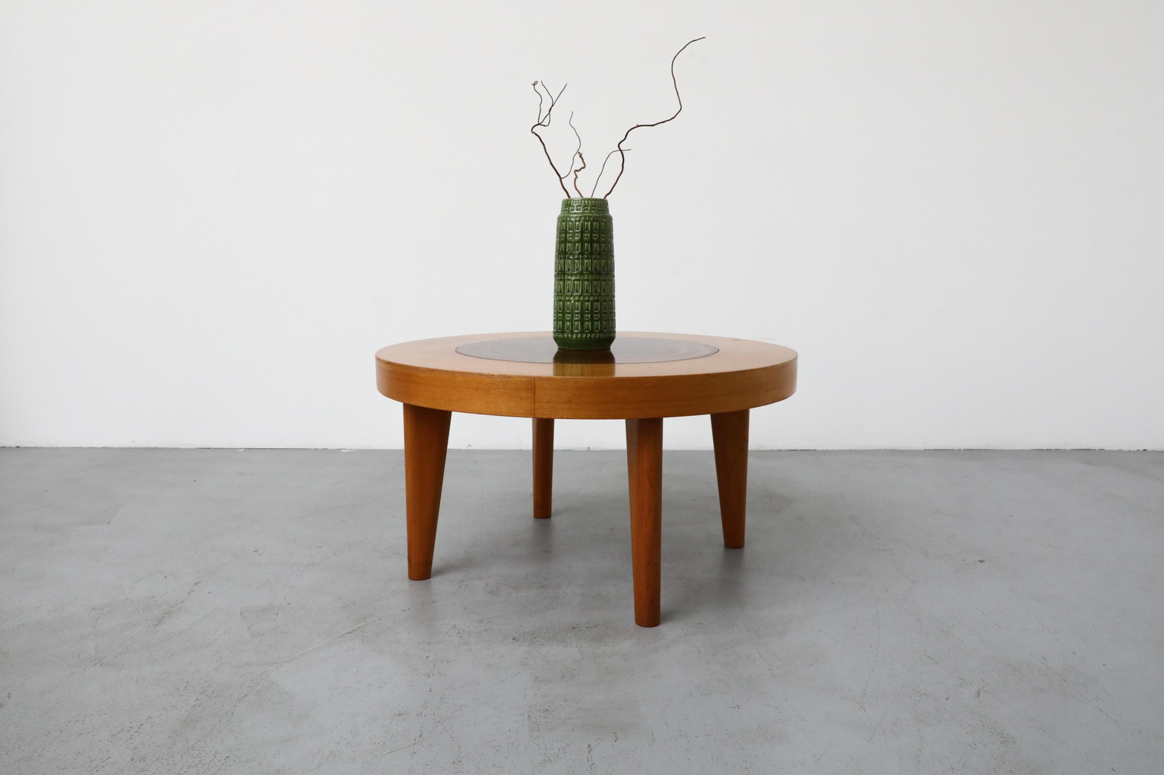 Attractive and heavy! This two-tone wood table has a round mid-toned veneer top with beautiful inset tree trunk center design and solid tapered compass legs, adding extra visual interest to this unique piece. In original condition with wear