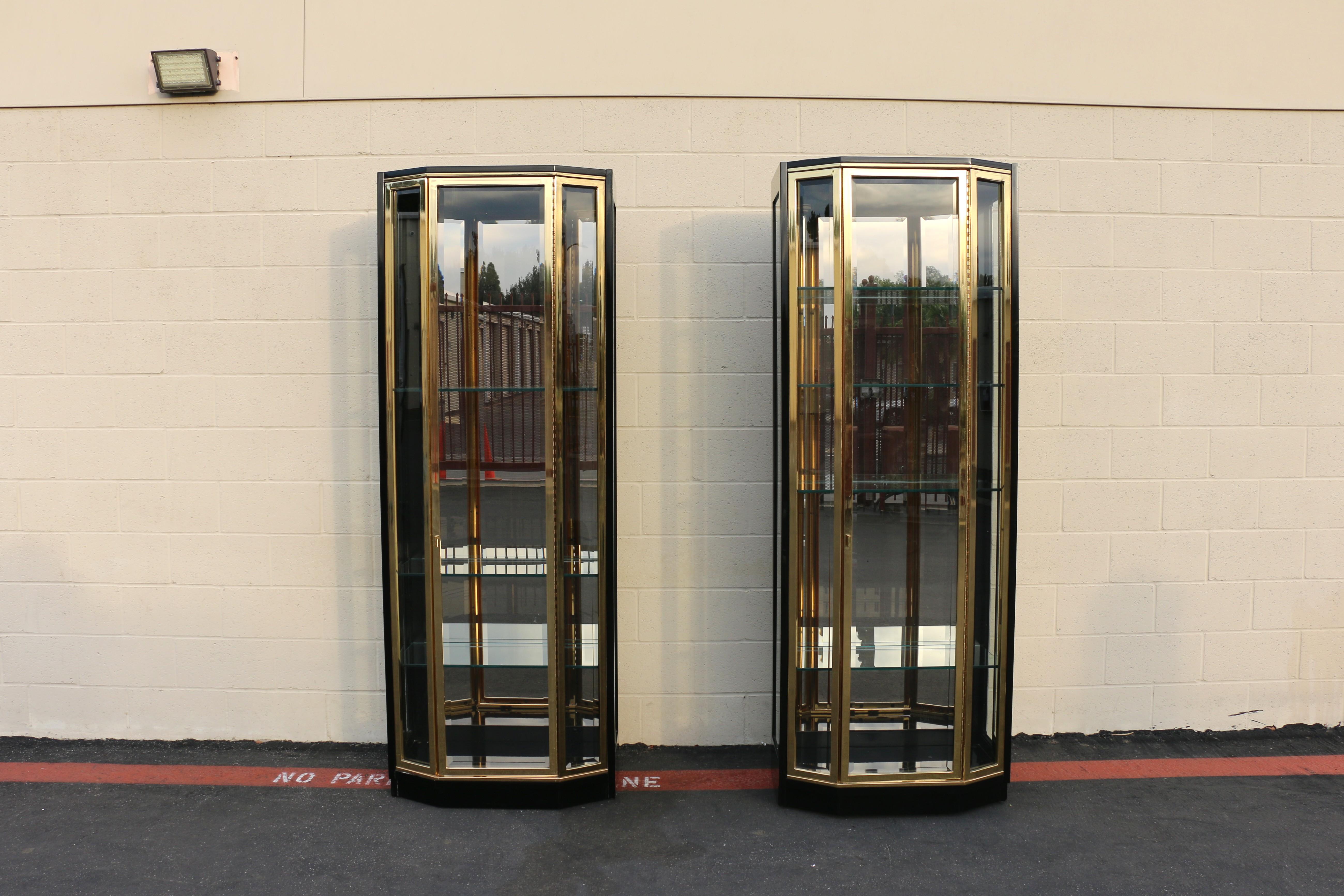 Spettacolare coppia di vetrine alte disegnate da Henredon, ciascuna realizzata con un'imponente struttura laccata nera e finiture in ottone sulle porte e sui bordi.
Gli armadietti sono caratterizzati da lati e porte in vetro smussato, pannelli