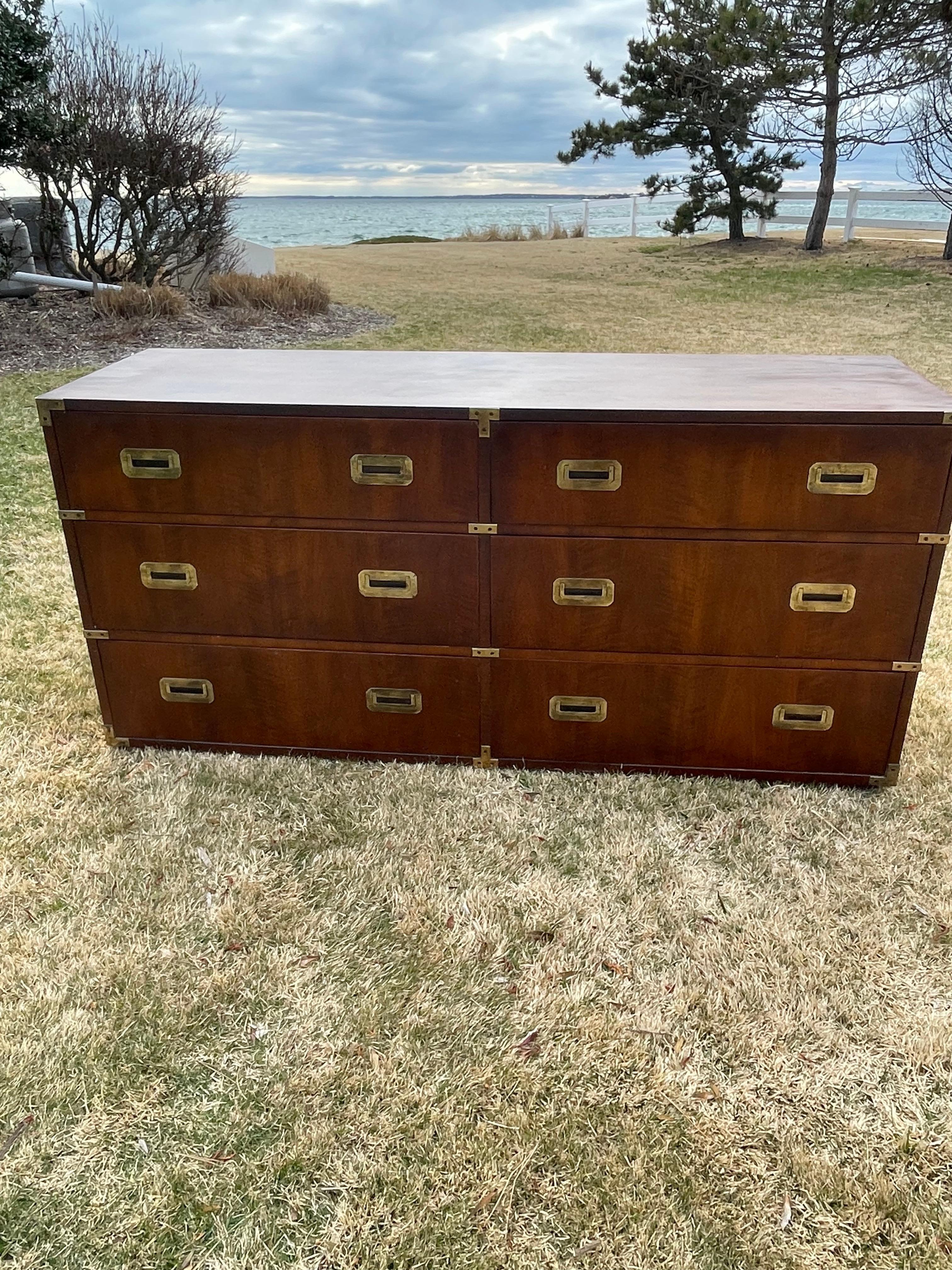 Handsome walnut and brass dresser with six drawers . This dresser was part of the Campaign Series made by Henredon .The front edges are capped in brass and the drawers have brass inset pulls with plenty of storage . One drawer has divided spaces for