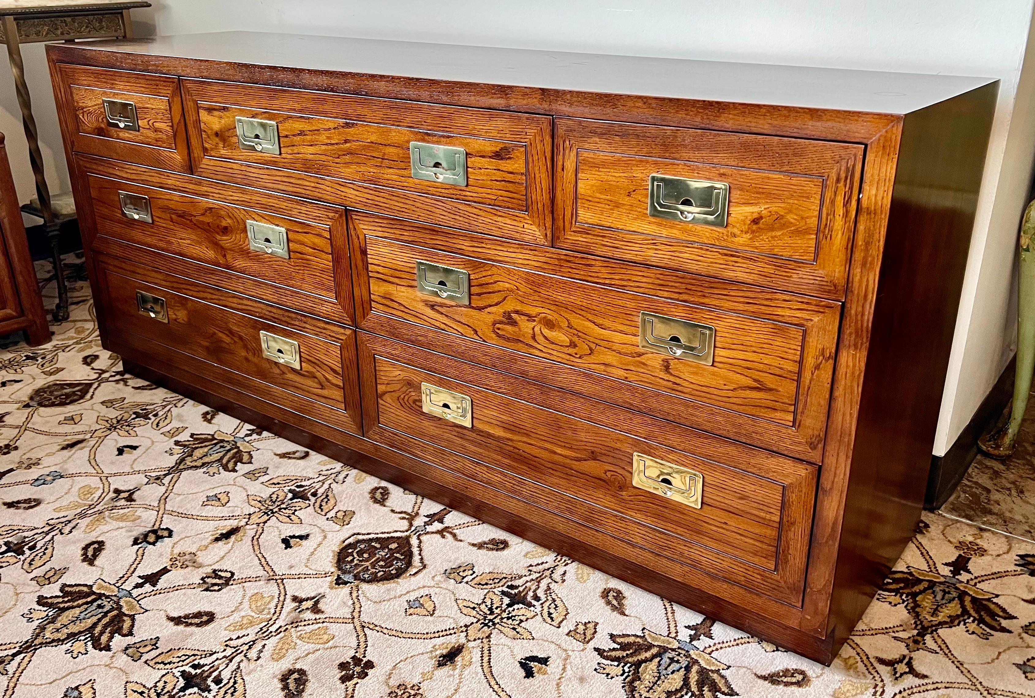 Midcentury classic Henredon campaign style walnut dresser has seven dovetailed drawers which include four larger drawers below and three smaller ones at the top to provide ample storage. Drawers are fitted with inset brass pulls. Interior of one