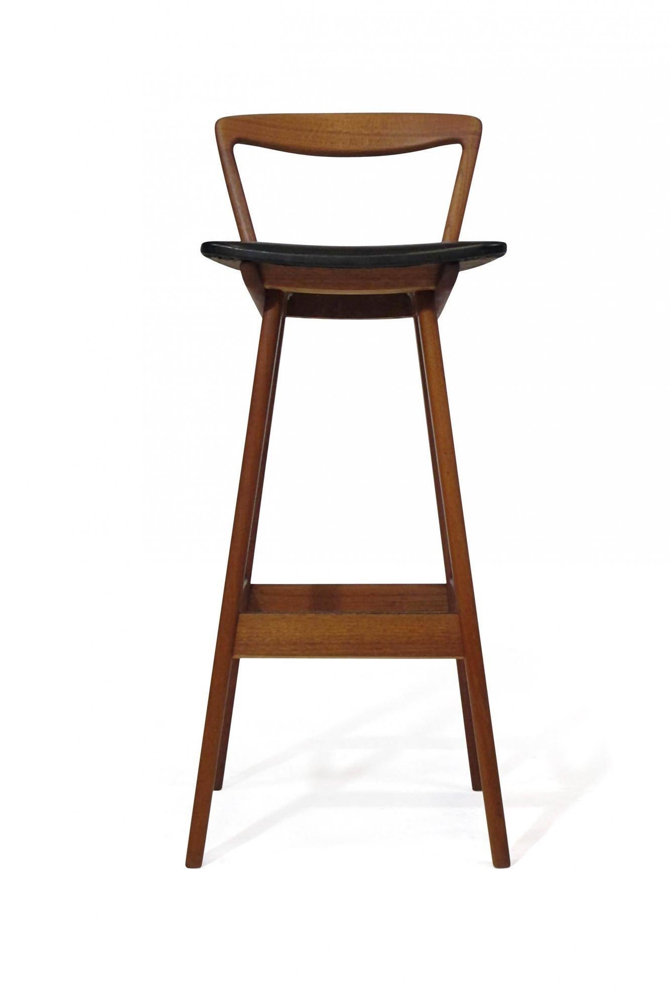 midcentury teak bar stool designed by Henry Rosengren Hansen for Brande Mobelfabrik model 43, Denmark. Barstool crafted of solid teak frame, elegantly sculpted backrest with the original black vinyl seat, raised on flared legs. Excellent condition