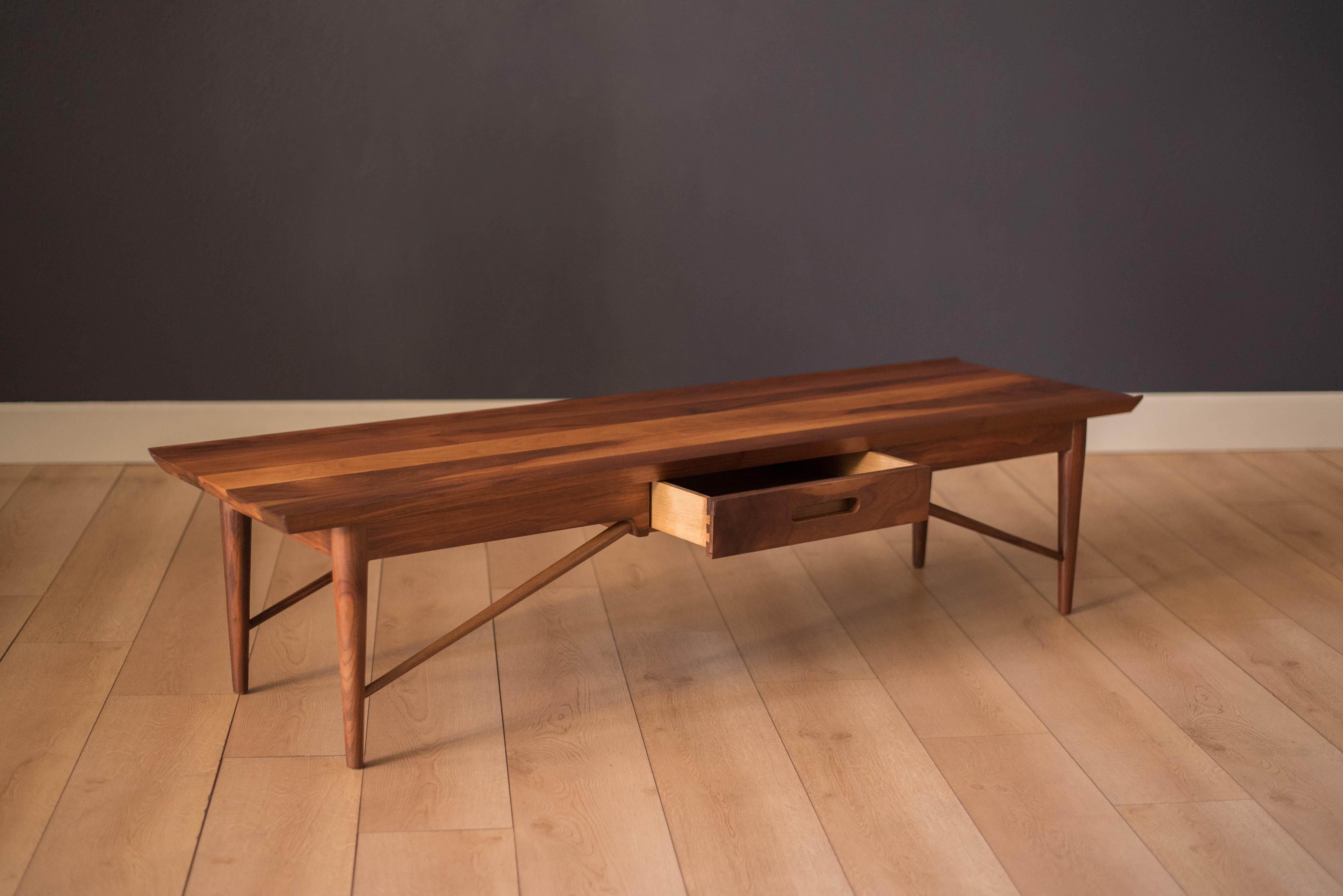 Vintage coffee table by Heritage Henredon, circa 1960s. This piece features a solid planked walnut top and sculpted frame. Includes one dovetailed storage drawer and can be displayed from any angle with a finished back.