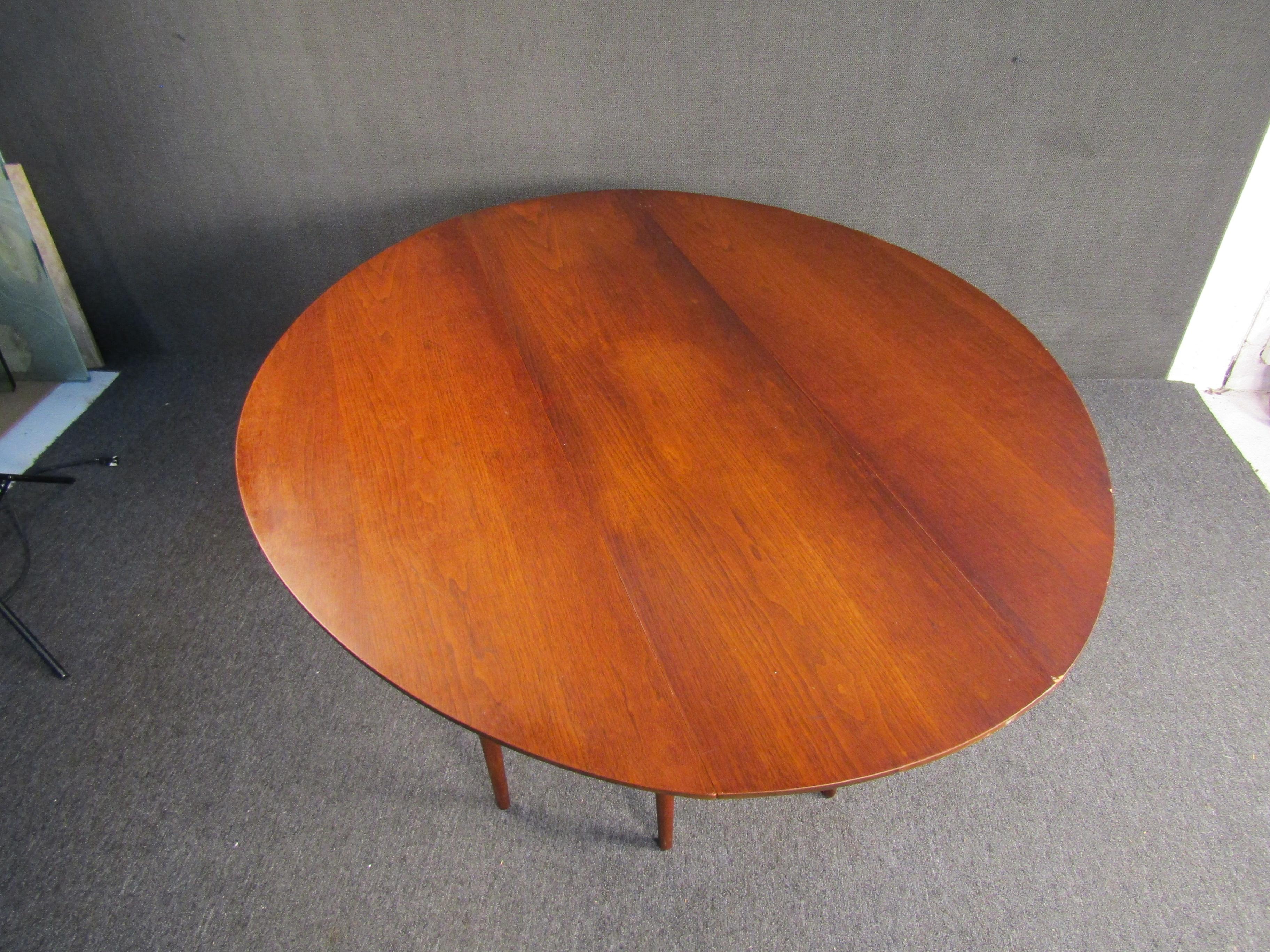 Beautiful walnut gateleg dining table by Heritage-Henredon, circa 1960s. Featuring tapered legs and two folding leaves which expand the table from 19.5