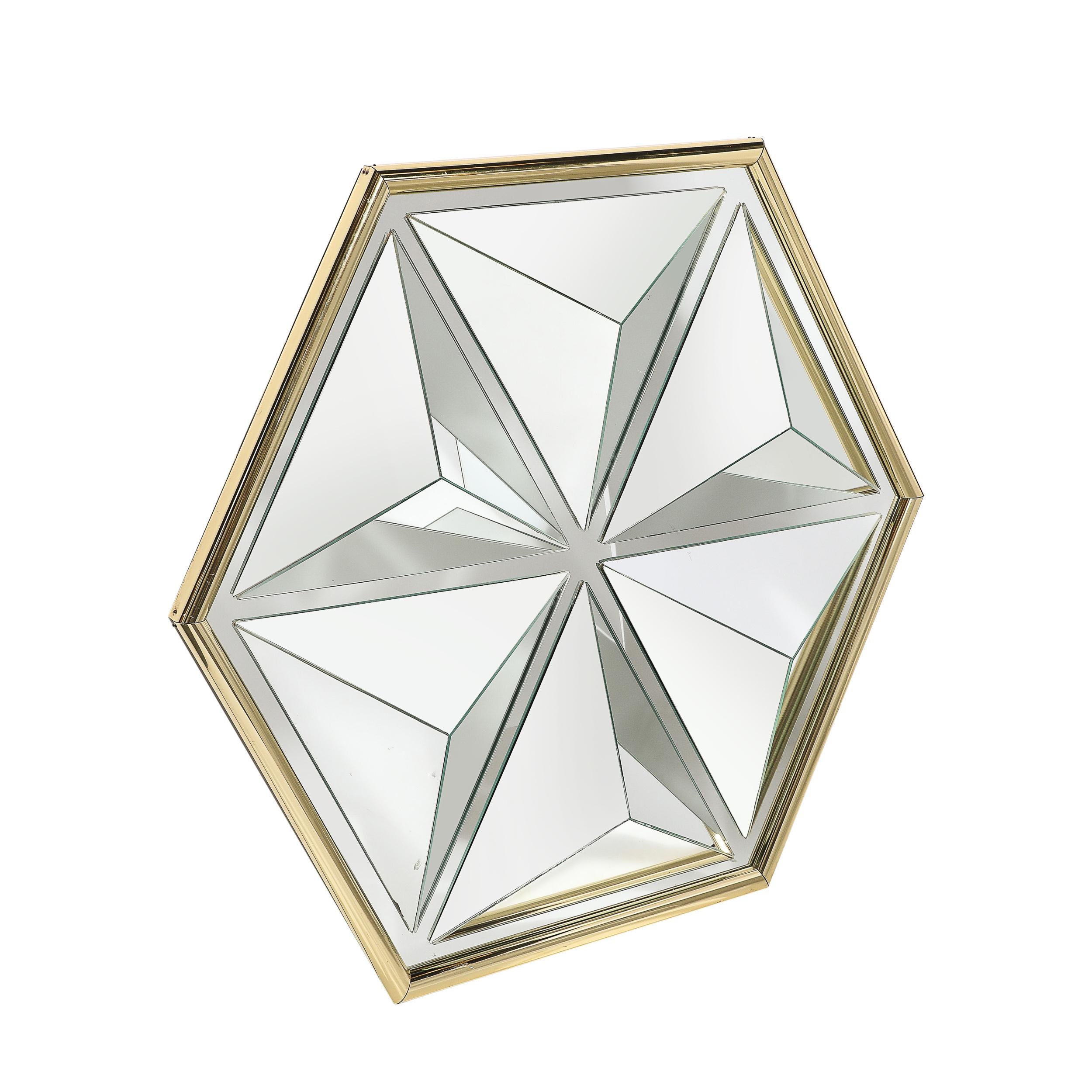 Ce remarquable miroir hexagonal de style moderniste du milieu du siècle, fabriqué en Amérique vers 1980, est une pièce décorative captivante à la présence audacieuse et sculpturale. Doté d'un design kaléidoscopique segmenté, la disposition