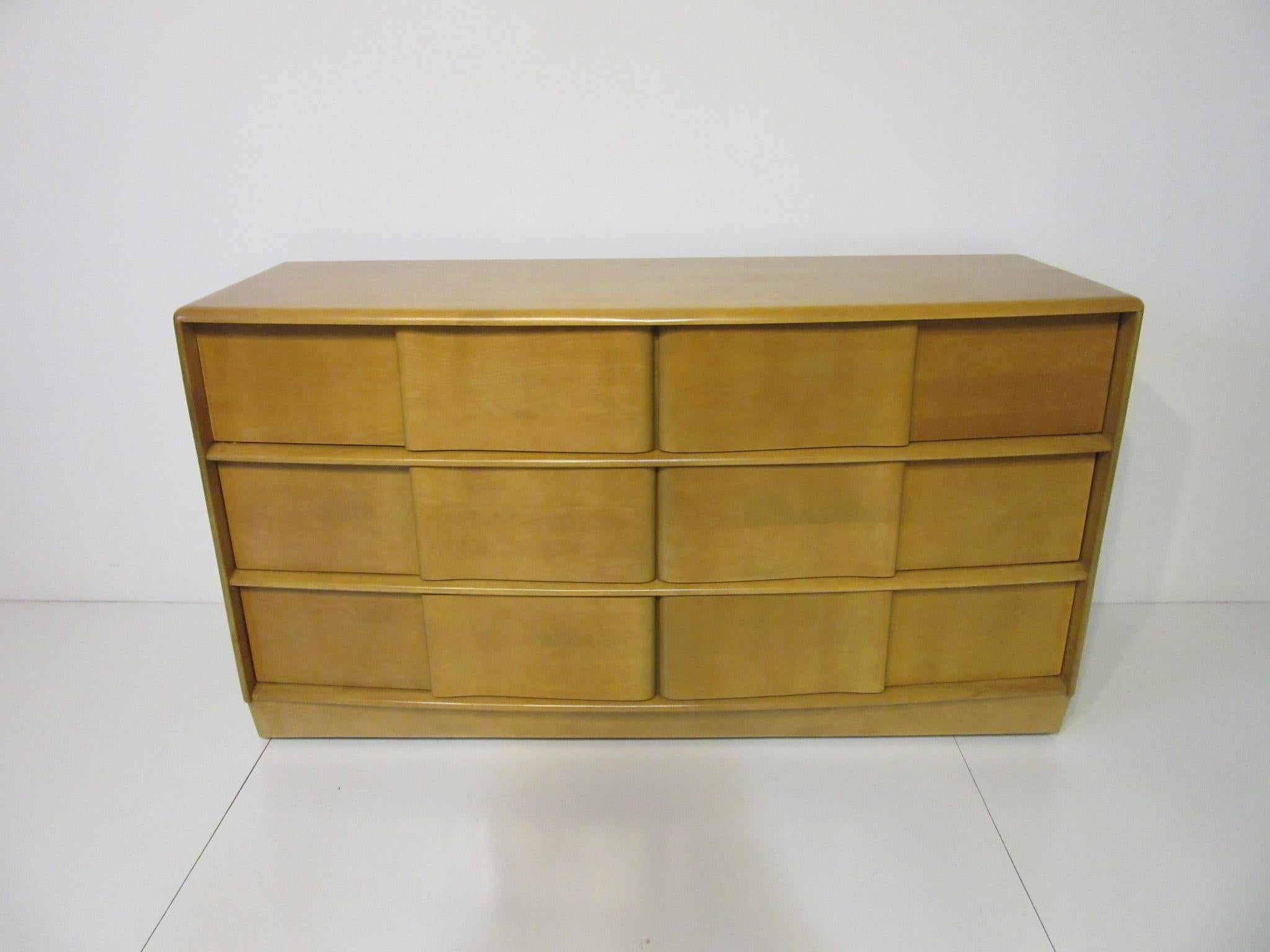A larger sculptural front six-drawer solid wood dresser in a wheat tone finish with wheels and plenty of storage, this restored piece is from the Sculptura collection manufactured by the Heywood-Wakefield Furniture company.