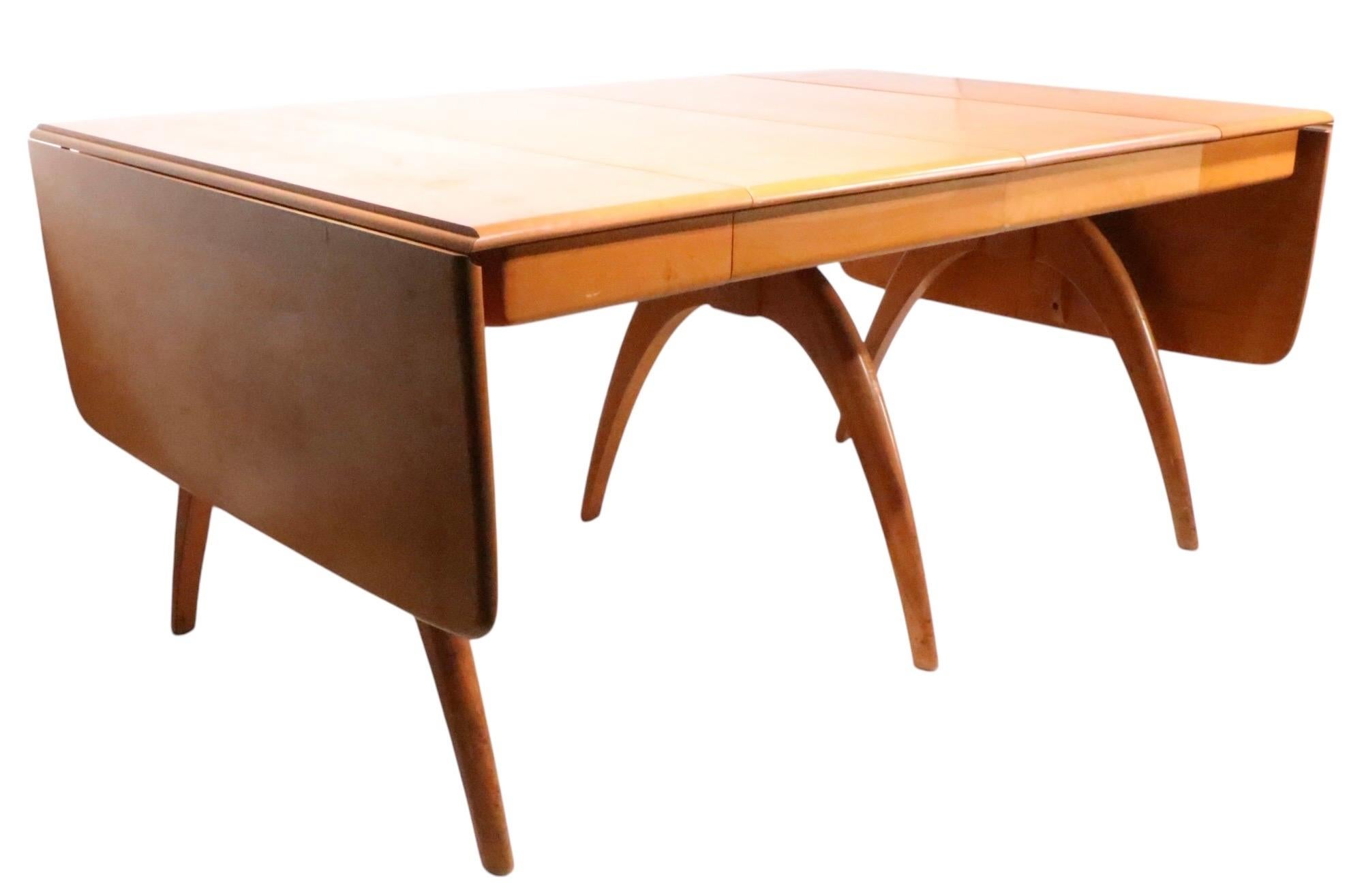 Classic Heywood Wakefield wishbone drop leaf table, with two leaves. The table features three dramatic wishbone form legs, two long drop leaves, and two large leaves, making it very versatile. This example is in good overall condition, having some