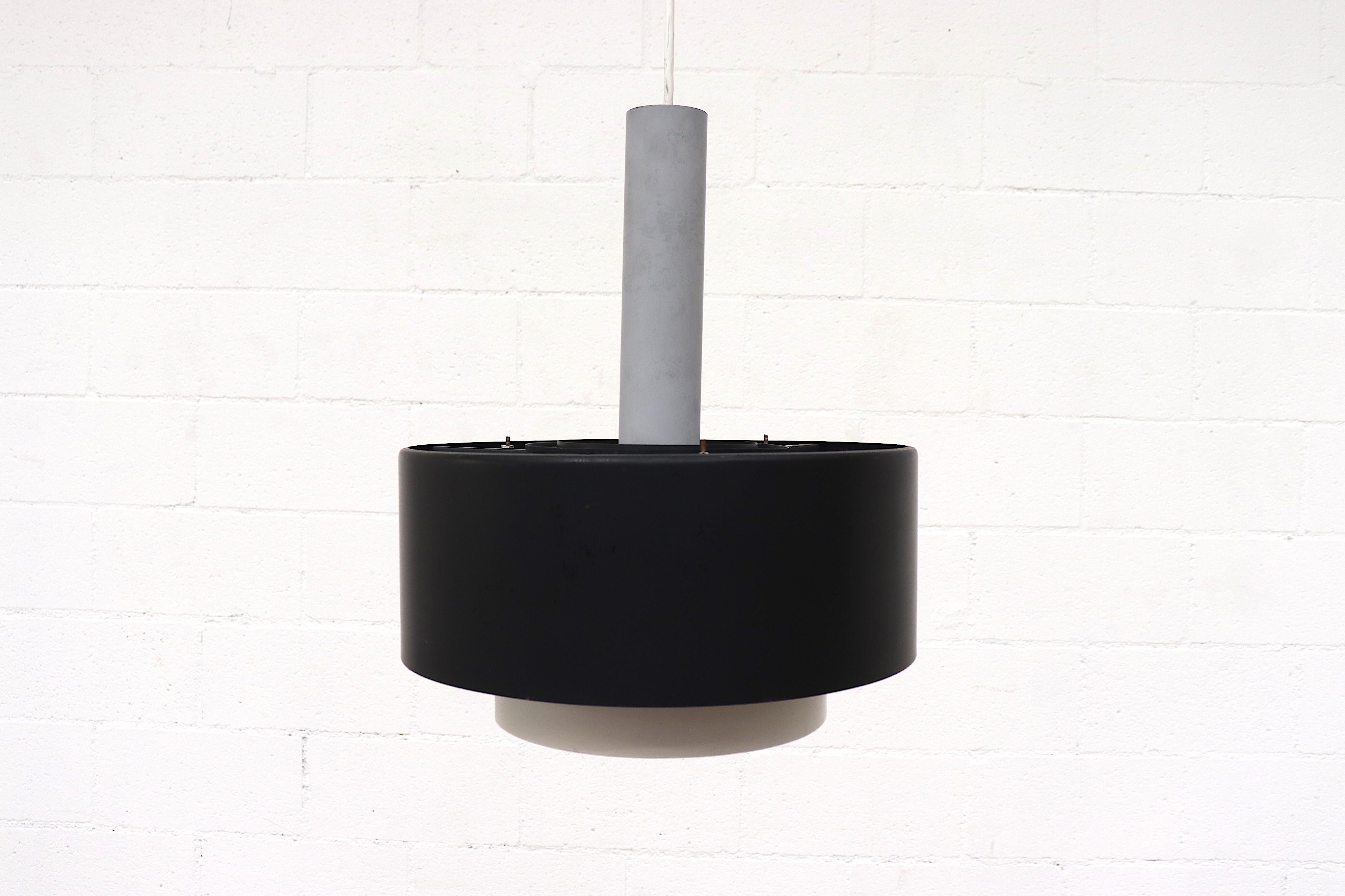 Midcentury industrial ceiling pendant with black and white enameled shade on tubular grey metal hardware with standard light socket. In original condition with wear and scratching consistent with age ad use. Individually priced.