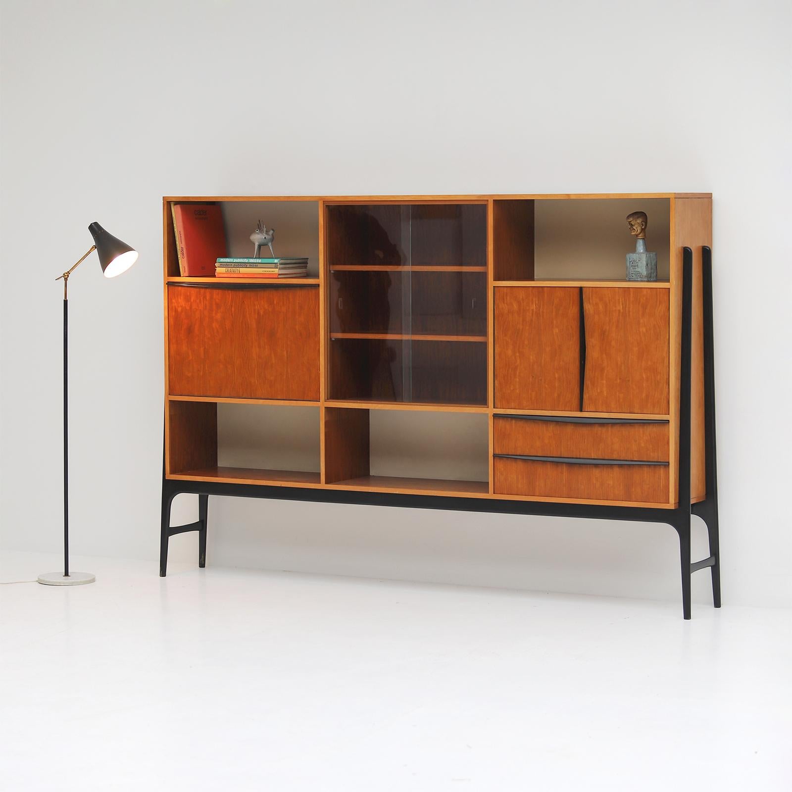 Very rare highboard designed by Alfred Hendrickx for Belform in the 1950s. This unique sideboard is a decorative eye catcher and made from a beautiful patterned wood resting on a black lacquered frame. A folding bar with mirrored glass is hidden