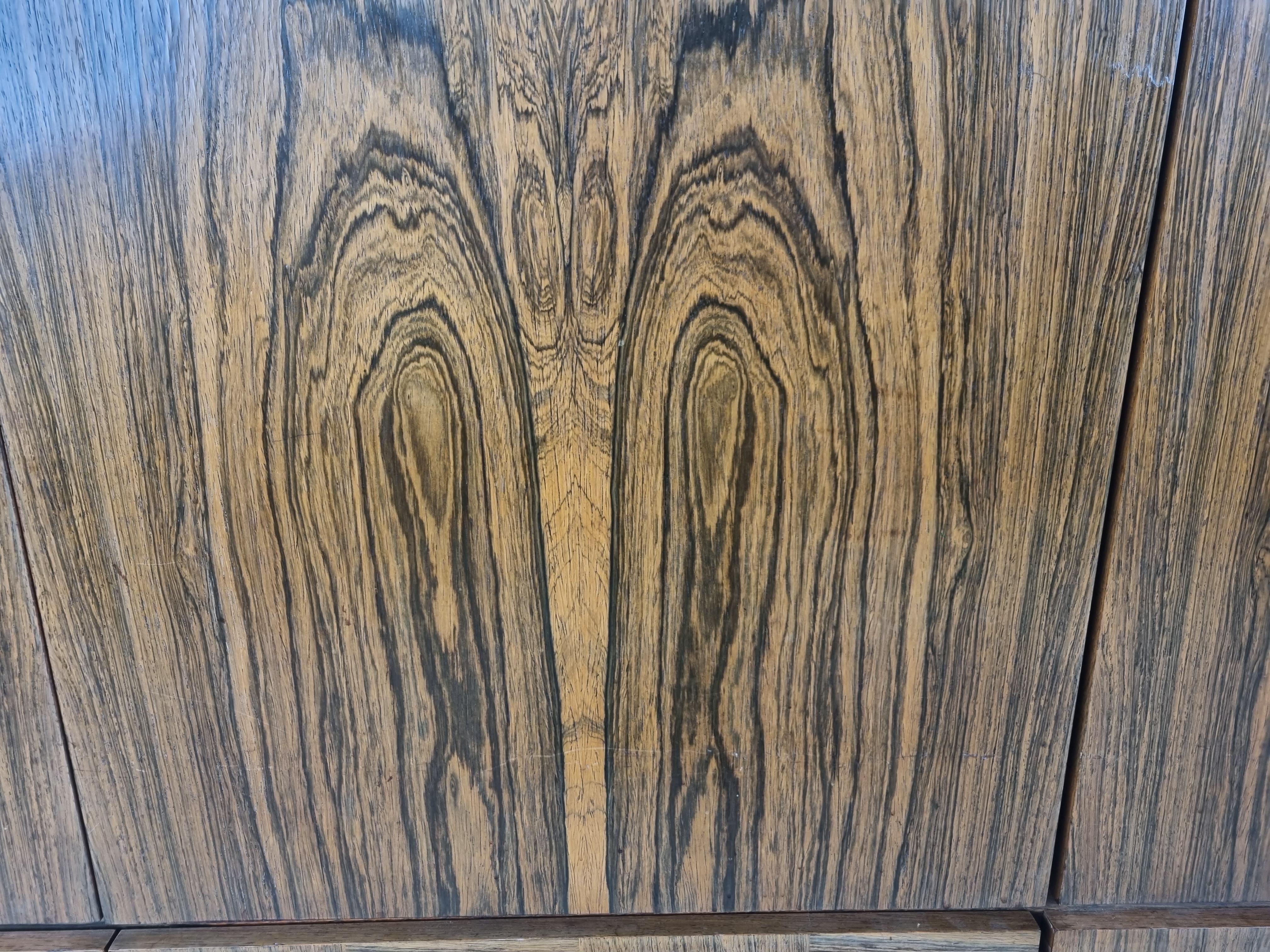 Great looking mid-century highboard or sideboard with beautiful motive veneer wood and a chrome and wooden base.

The sideboard consists of 4 doors and 4 drawers providing loads of storage space.

Very much in the style of Rudolf Glatzel's