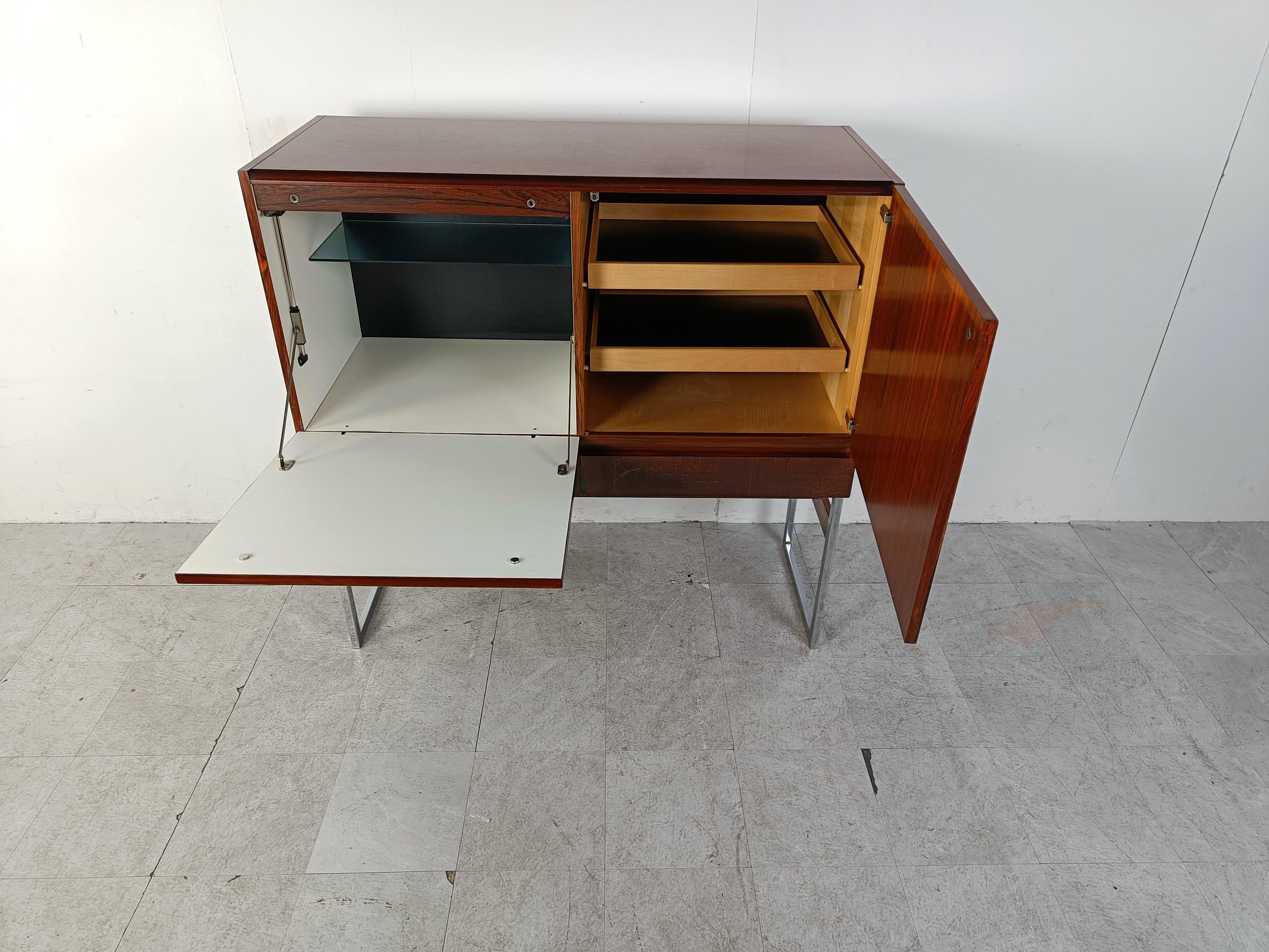 Great looking mid century bar cabinet with beautiful veneer wood and a chrome and wooden base.

The bar cabinet consists of 2 doors and 2 drawers providing loads of storage space.

Very much in the style of Rudolf Glatzel's design, this sideboard