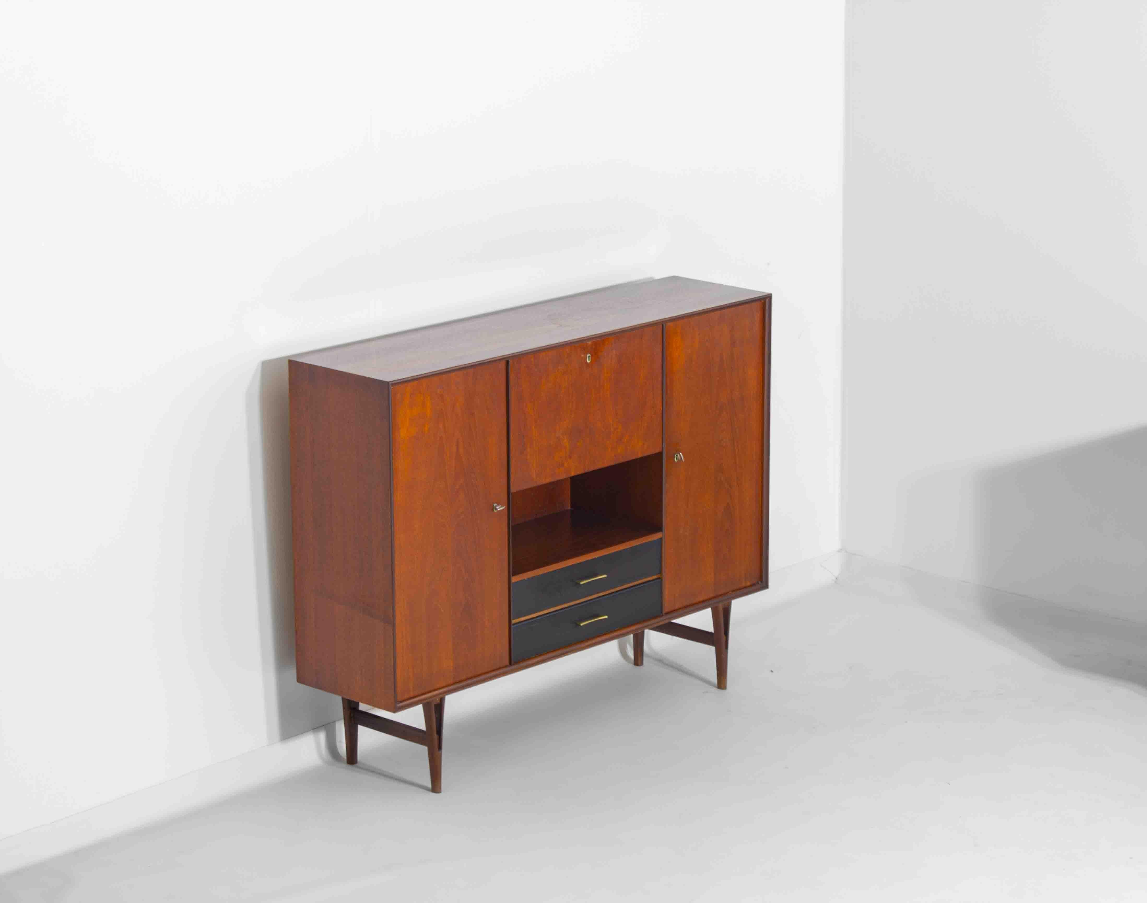 This Belgian highboard by Van Pelt from the 1960s has a teak body with black drawers and brass handles. It offers a mix of cabinets and drawers for plenty of storage. The V-shaped legs give it a distinct look while keeping it sturdy. A solid,