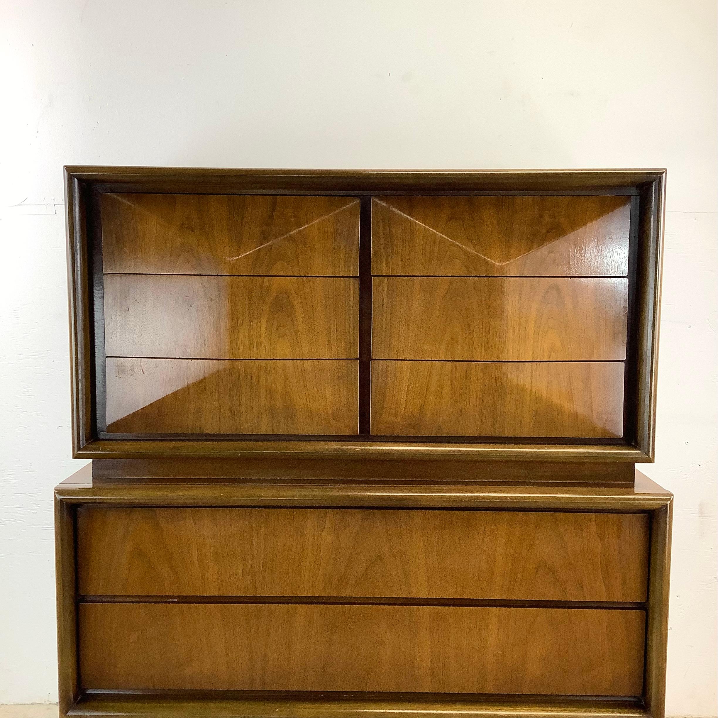 Elevate your living space with this mid-century walnut highboy from United Furniture, a sought after manufacturer of vintage modern design. This tall eight drawer dresser, with its streamlined silhouette and rich walnut finish, embodies the