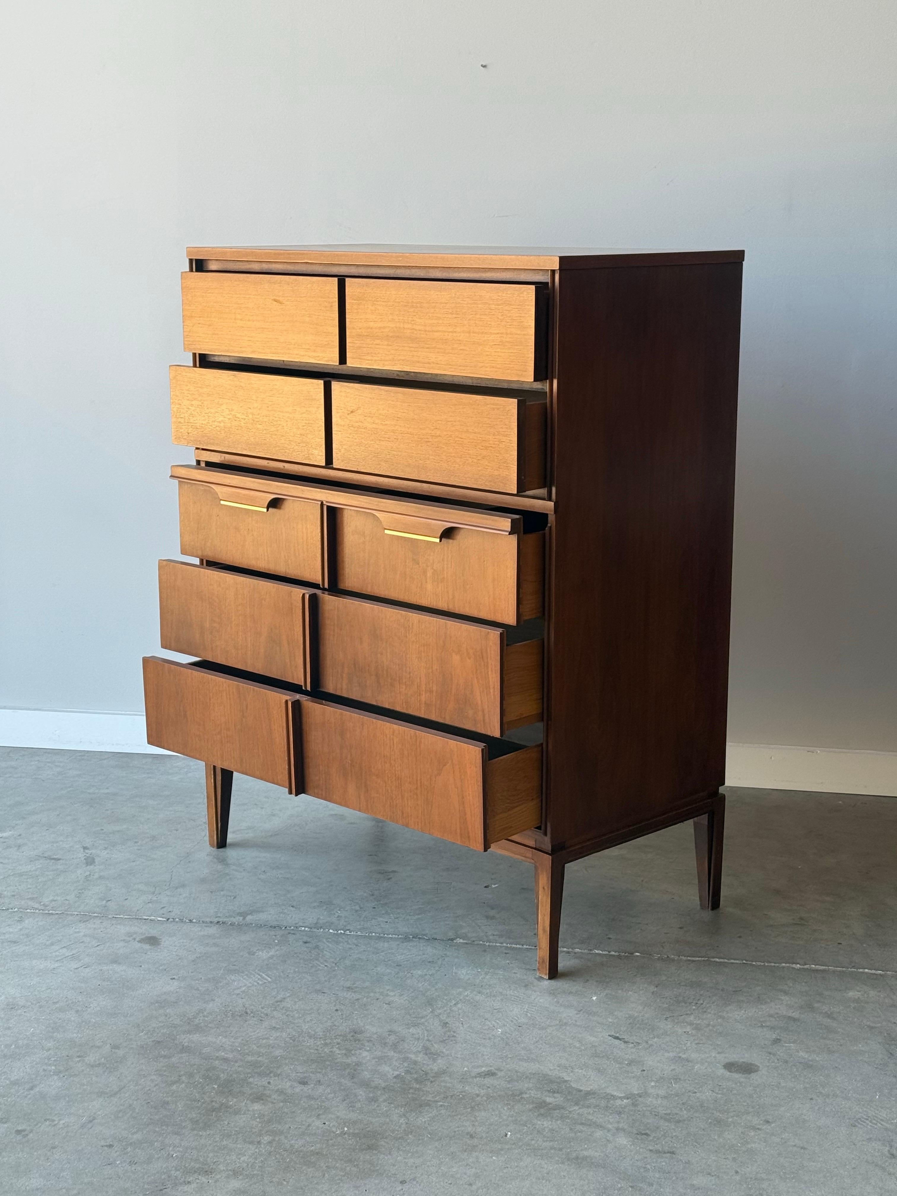 Mid-century highboy dresser designed by Basic Witz Furniture. Made from walnut wood and featuring five drawers. The drawers are a bit visually deceptive as they are framed to look like two drawers side by side, yet are one long spacious drawer. The
