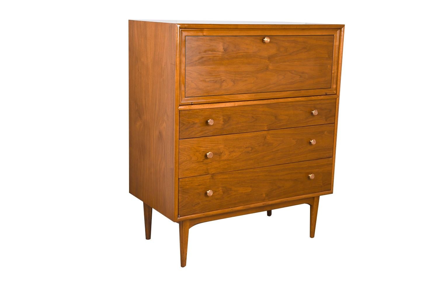 An elegant Mid-Century Modern tall dresser/highboy/chest of drawers designed by Kipp Stewart and Stewart MacDougall for Drexel’s Declaration Collection, circa 1960’s. Featuring a solid, beautifully grained walnut wood case and frame. The upper drop