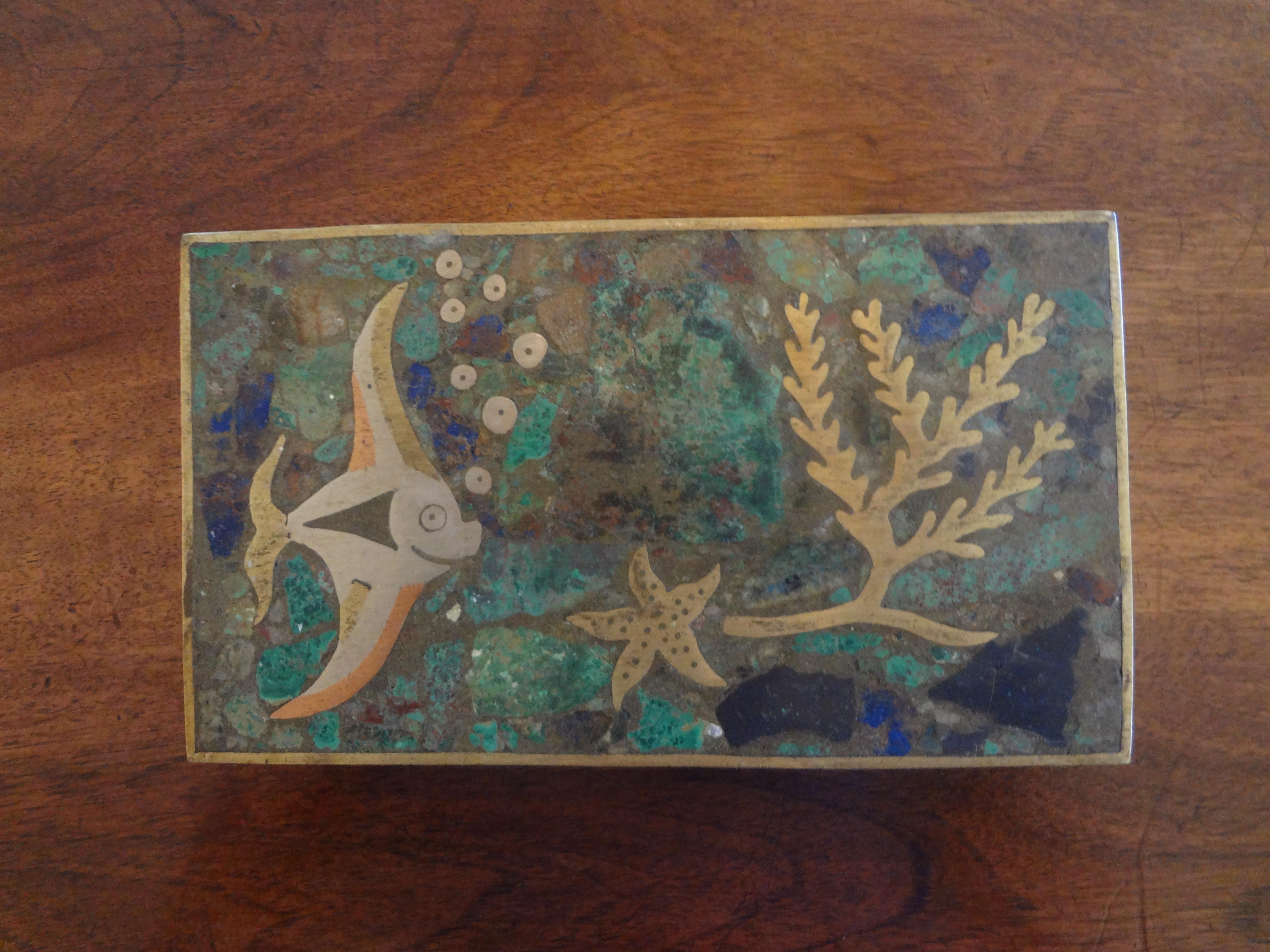 Stunning Mexican midcentury hinged brass box with wood interior featuring sealife. The lid of this decorative brass box is of mixed metals and semi precious stones with an angel fish, a star fish and coral.
Stamped Mexico on the bottom. This
