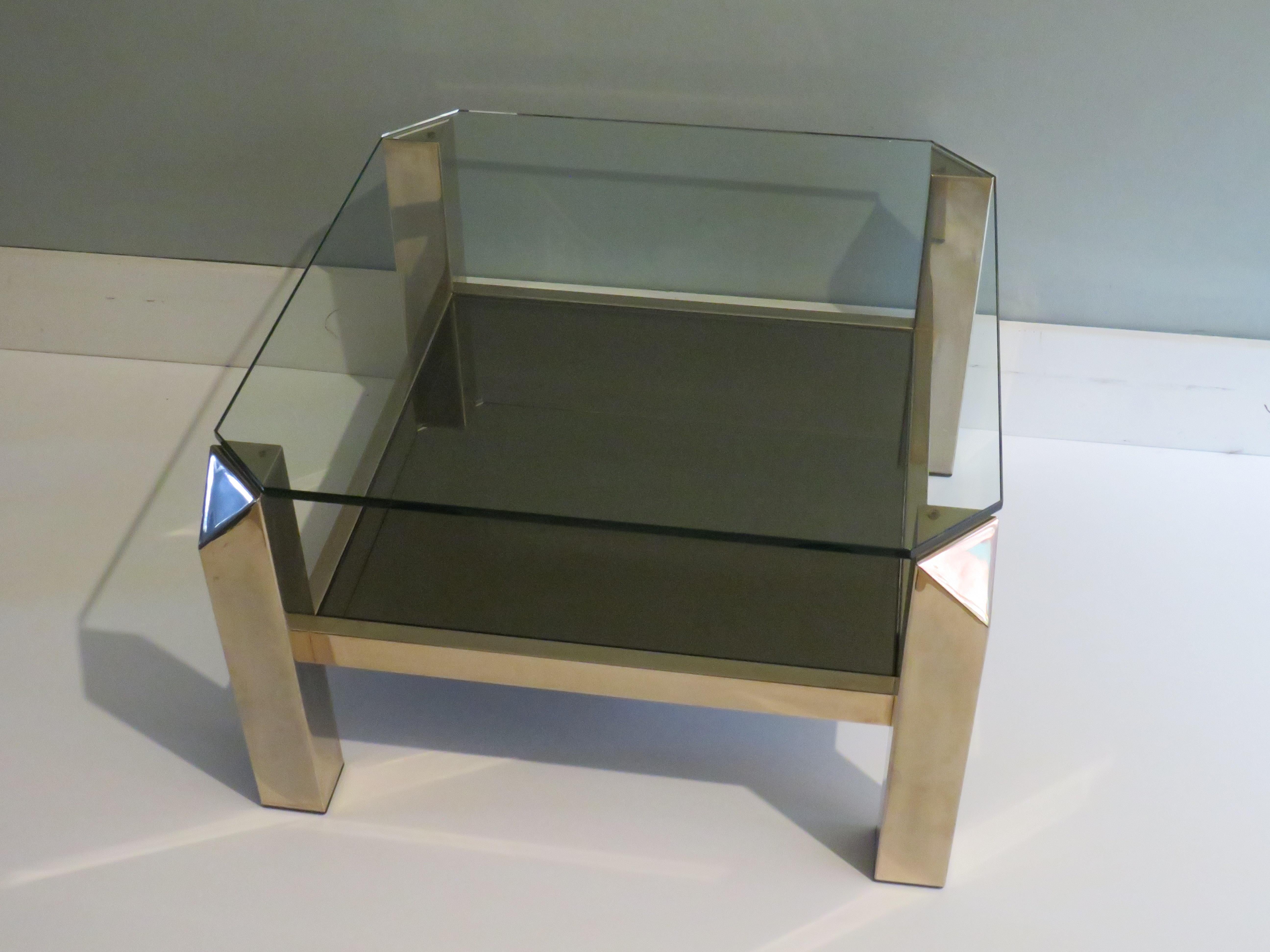 Square coffee table in 23 carat gold-plated metal base and 2 glass tops.
The lower top is made of smoked mirror glass and the upper top is made of transparent glass.
The frame has remarkable chamfered corners.
The height of the table is 37 cm, de