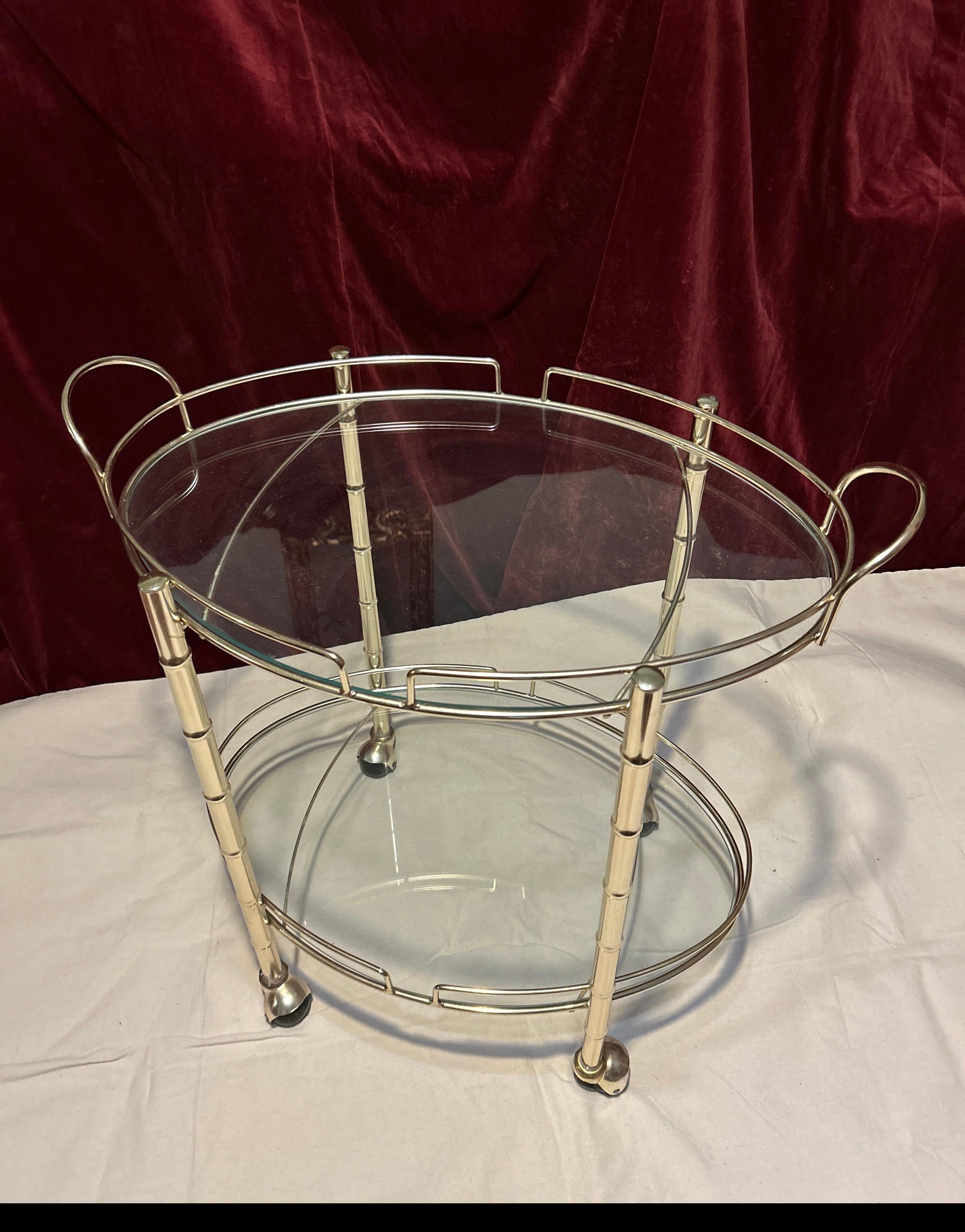 Interesting and fun bar cart on casters with original glass, handles and two tiers. Functional, yet aesthetic and well made with an oriental flair. A versatile and true Hollywood Regency gem not to be missed if you are looking to add finesse to your