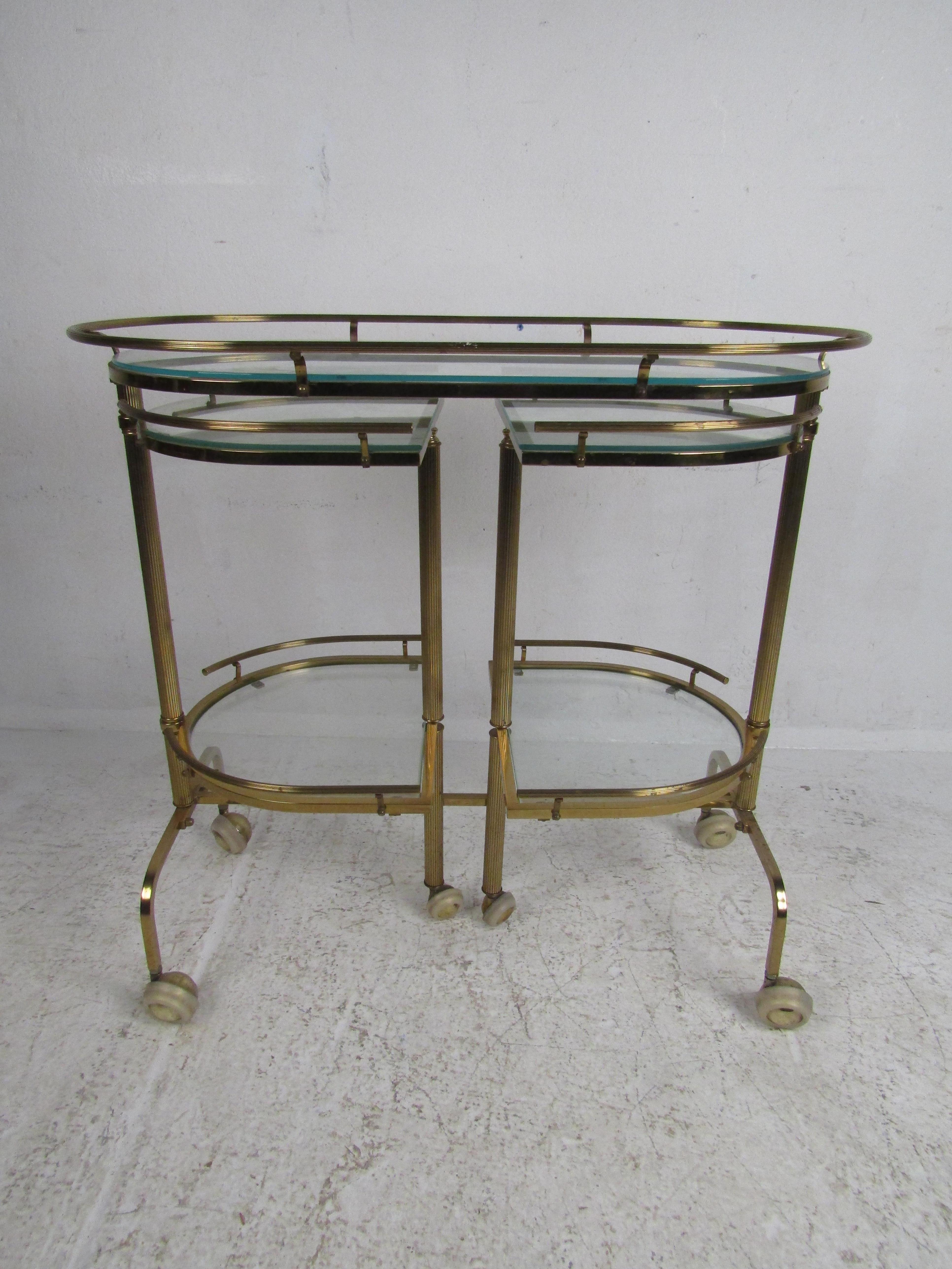 This truly unique three-tier glass top swivel bar cart features an eye-catching brass frame on rolling casters. Multi-tier swinging shelves make this a great piece to add to your home or office. When fully open it measures 55.5