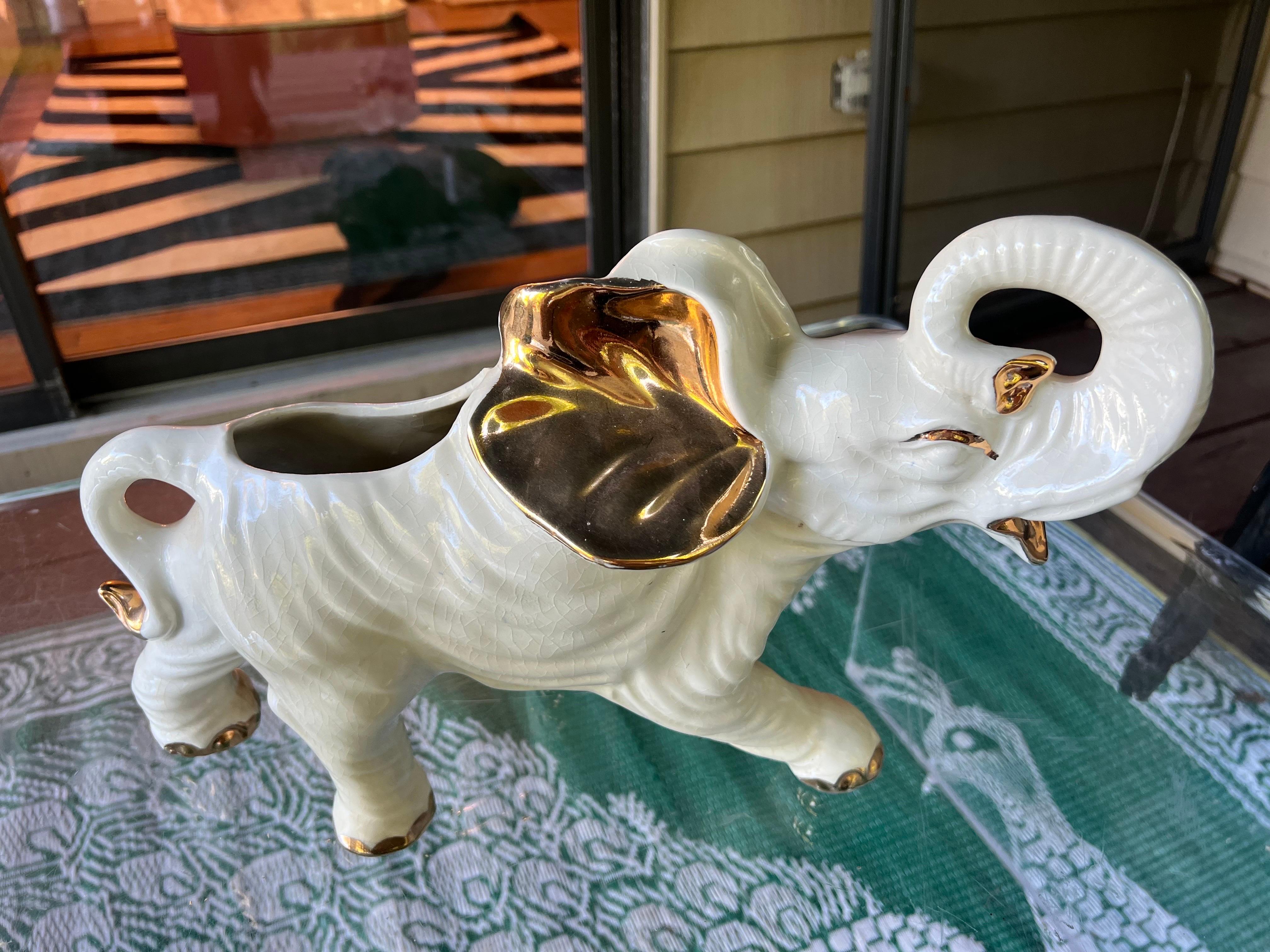Nous vous proposons cette jolie jardinière en céramique représentant un éléphant blanc, vraisemblablement produite au Japon entre les années 1950 et 1970. Ses traits sont soulignés d'or.