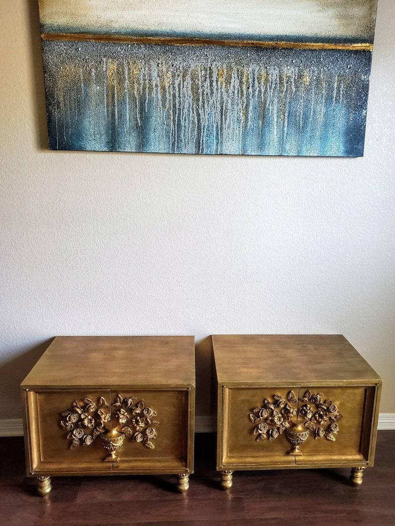 A wonderful pair of 1960s Hollywood Regency bedside cabinet nightstands (or side / end tables). Each having a rectangular wooden case in gilt gold painted finish, double doors opening to an adjustable interior shelf, the door fronts with beautiful