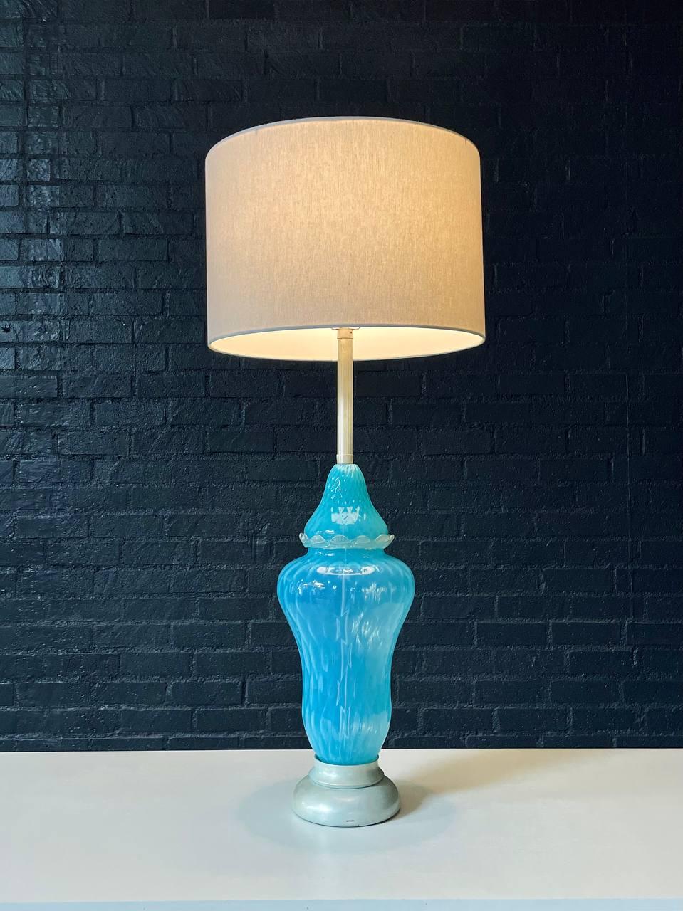 Condition: Newly Rewired, New Shade

Materials: Italian Murano Glass, New Shade

This Mid-Century Hollywood Regency table lamp features a stunning hand-blown Murano glass base in a vivid turquoise blue with elegant swirled patterns. Crafted in the