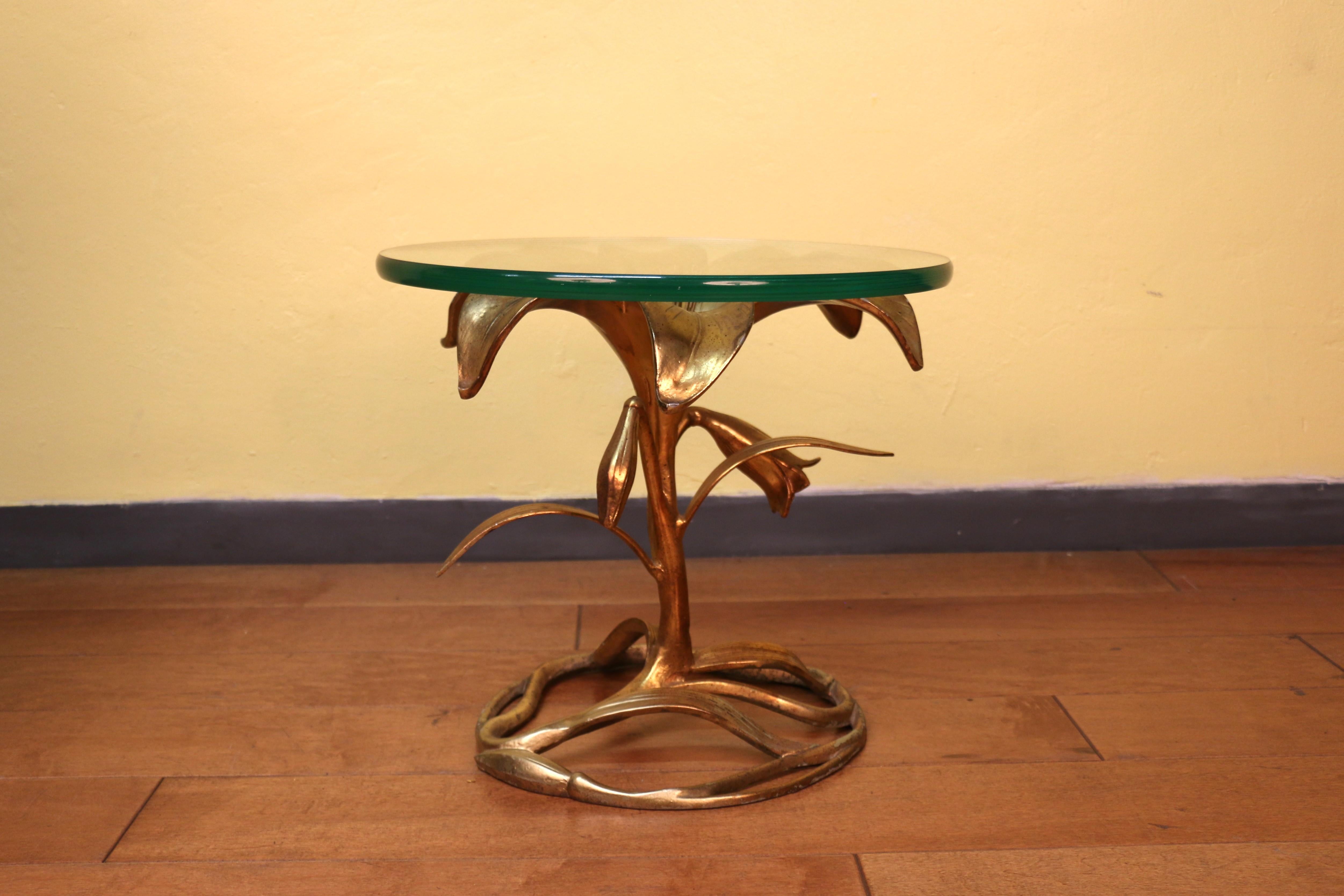 Wonderful side table designed by Arthur Court, USA, circa 1960. ( it has no maker’s mark). This stunning table is absolutely well executed, made of  gilded metal base that is featuring a lily leaf flower and it has a thick round glass top. The table