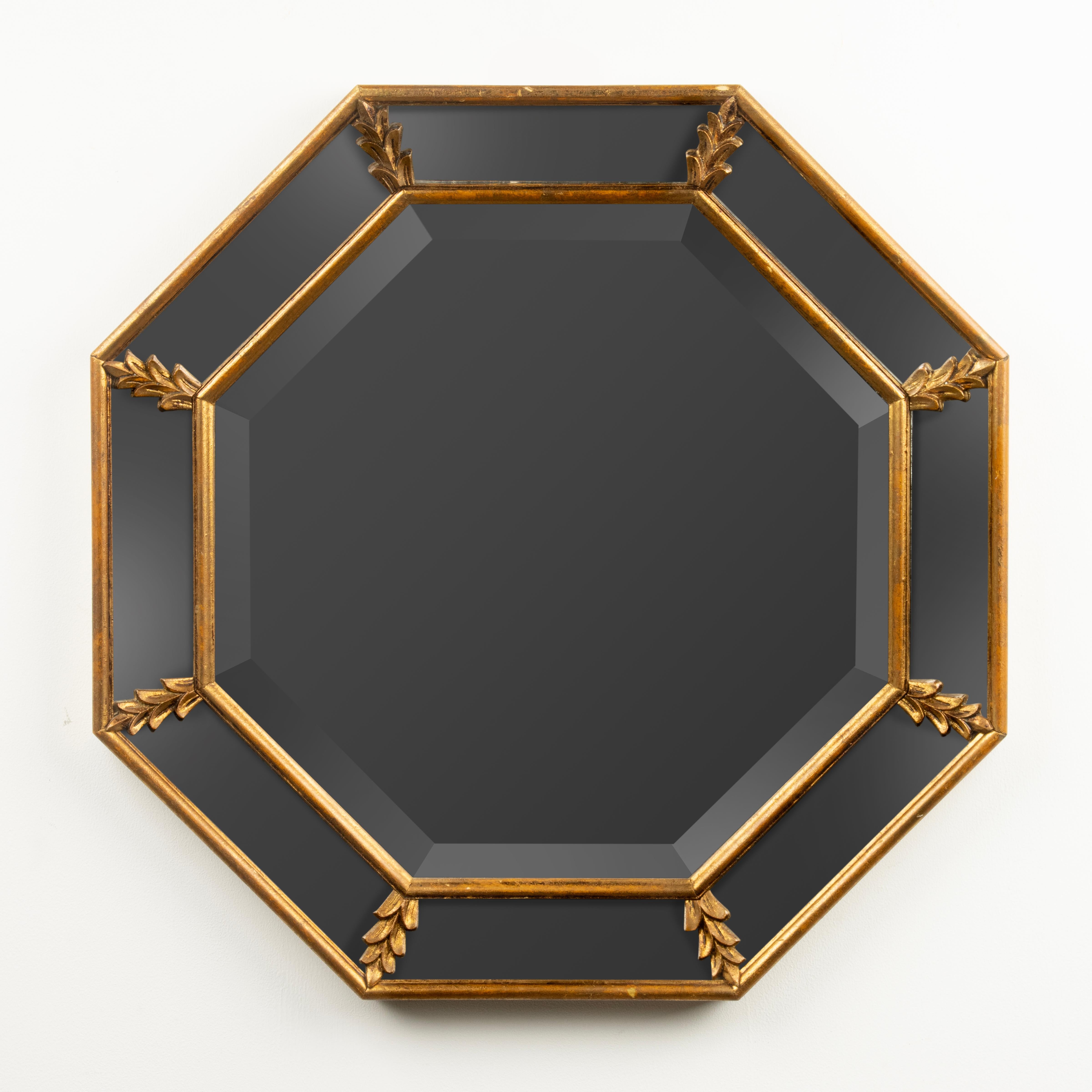 Magnifique miroir vintage de la période Hollywood Regency, vers 1960. Forme octogonale. 
Le cadre est en bois, magnifiquement patiné en rouge / or. Le rétroviseur est doté d'un vitrage latéral, également appelé 