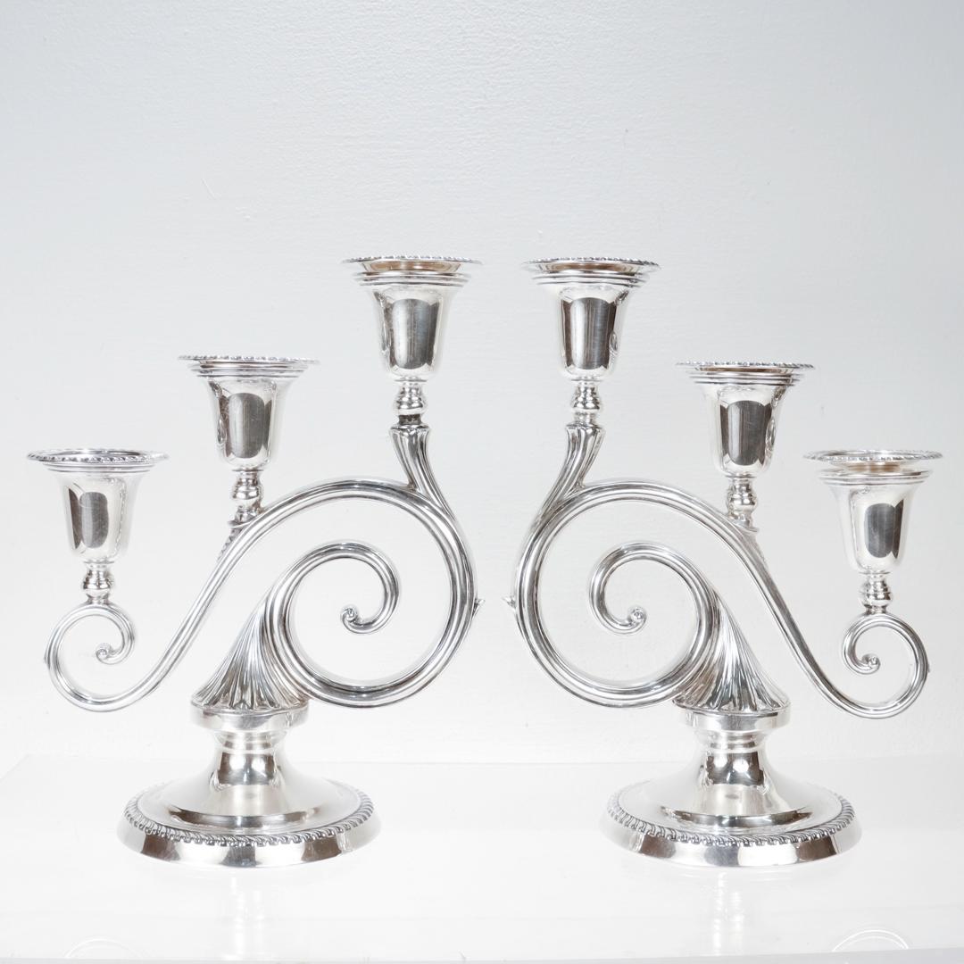 A fine pair of Hollywood Regency style three light weighted candelabra.

In sterling silver.

By Blackinton & Co.

Model no. A198.

Each candelabra with gadrooned bases supporting scrolling arms with 3 candle cups and removable bobeches.

Fully