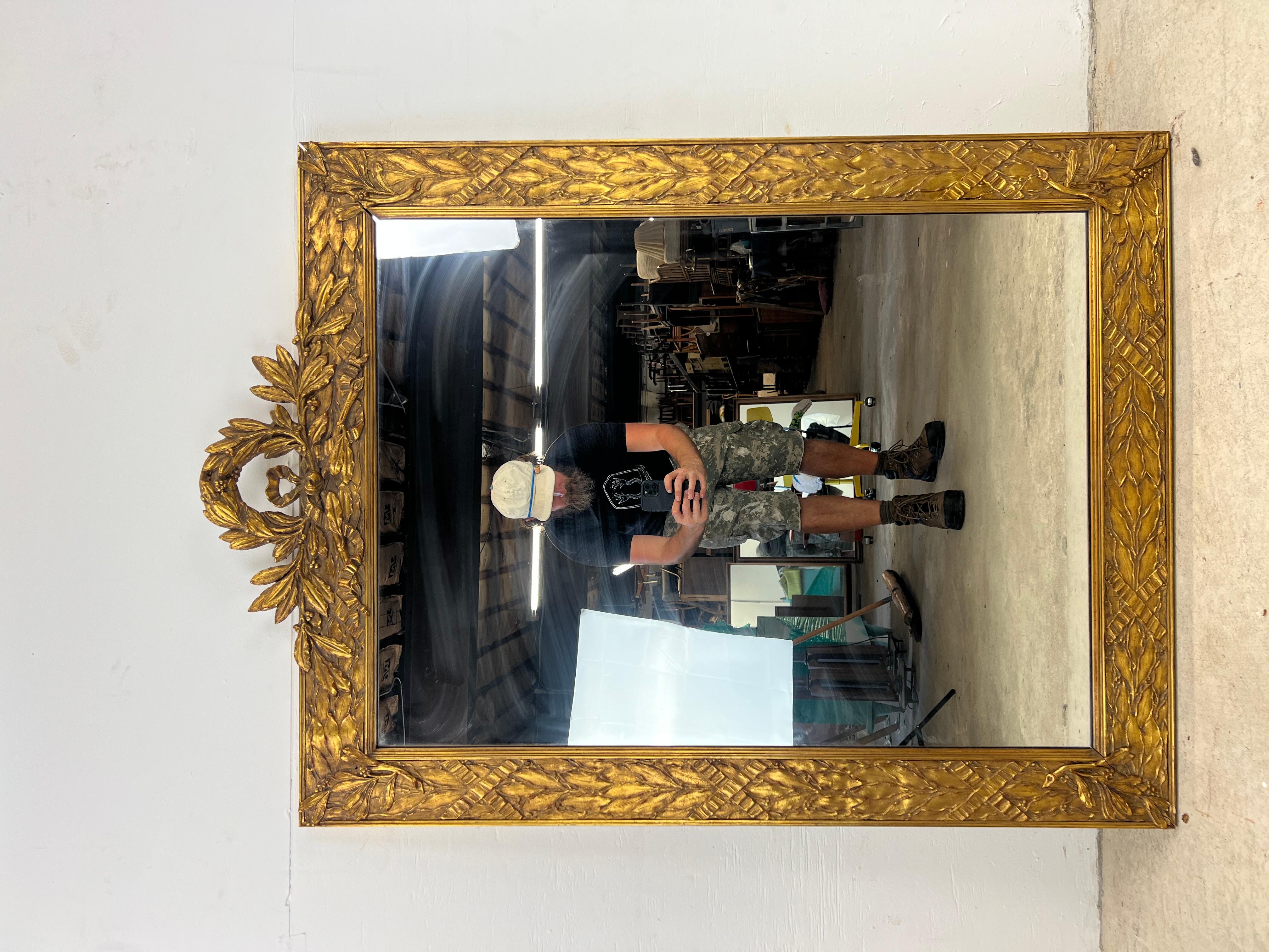 This mid century Hollywood regency style wall mirror features ornate frame with carved wood accents and gold leaf.

 Dimensions: 38w 1d 48h

Condition: Original gold leaf finish is in OK condition.  The wood frame has some damage to the ornate