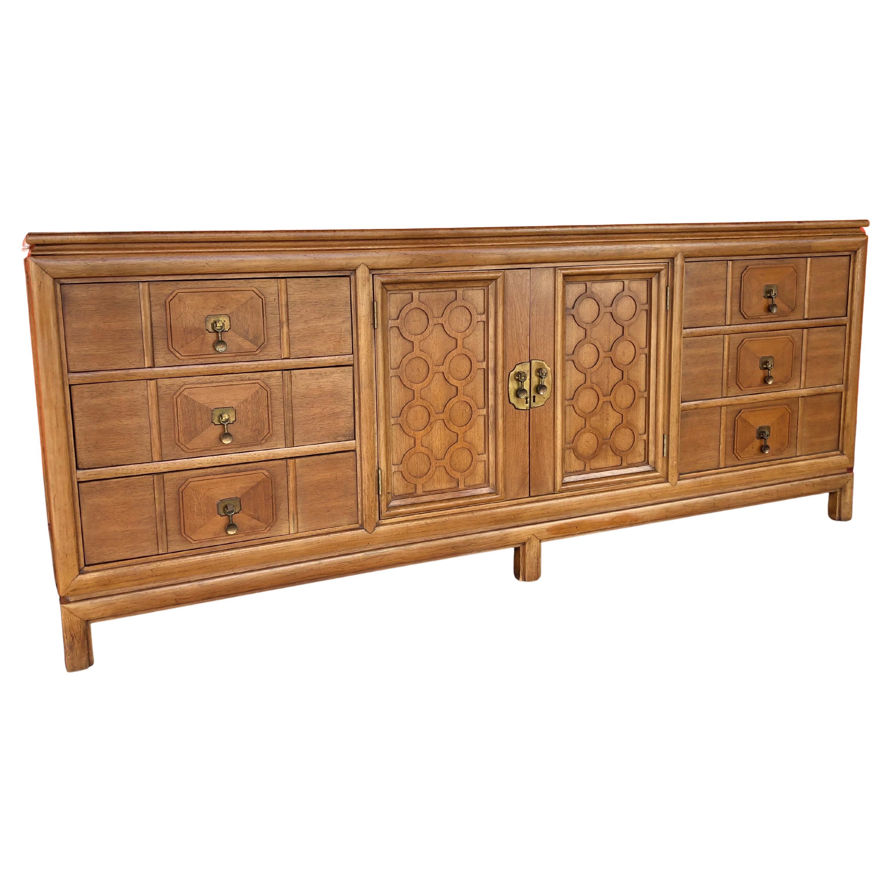 1960’s Hollywood Regency 5 piece pecan and burlwood bedroom set with brass hardware. Set consists of a nine drawer dresser, two small boy dressers or oversized nightstands, one headboard, and one mirror.

Well-made and built to last, this