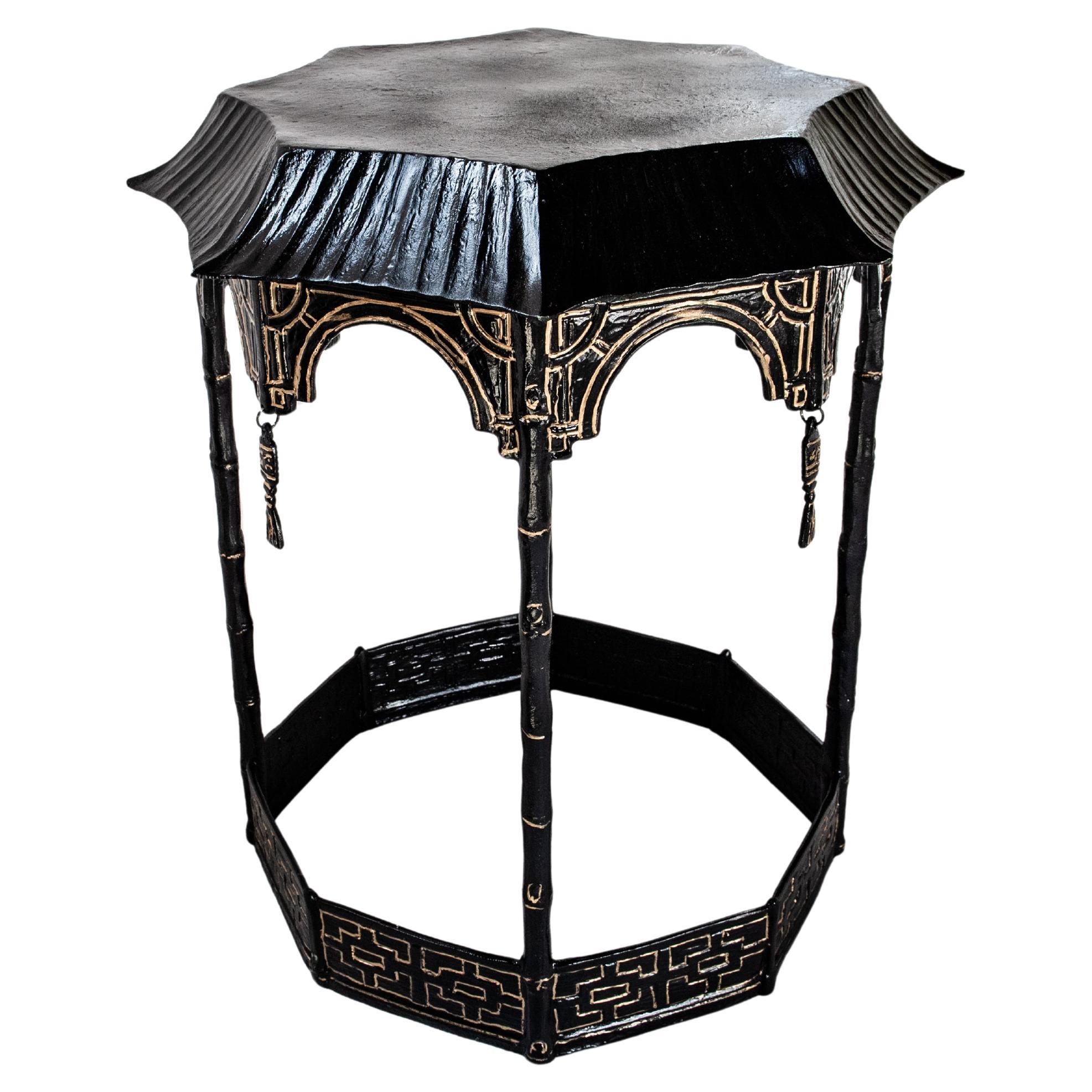 Table d'appoint fantaisiste de style Régence hollywoodienne peinte à la tôle.  Peinte en noir avec des accents dorés, la table est octogonale et en forme de pagode avec des glands en métal.  La table a un poids de métal vintage agréable. Il peut
