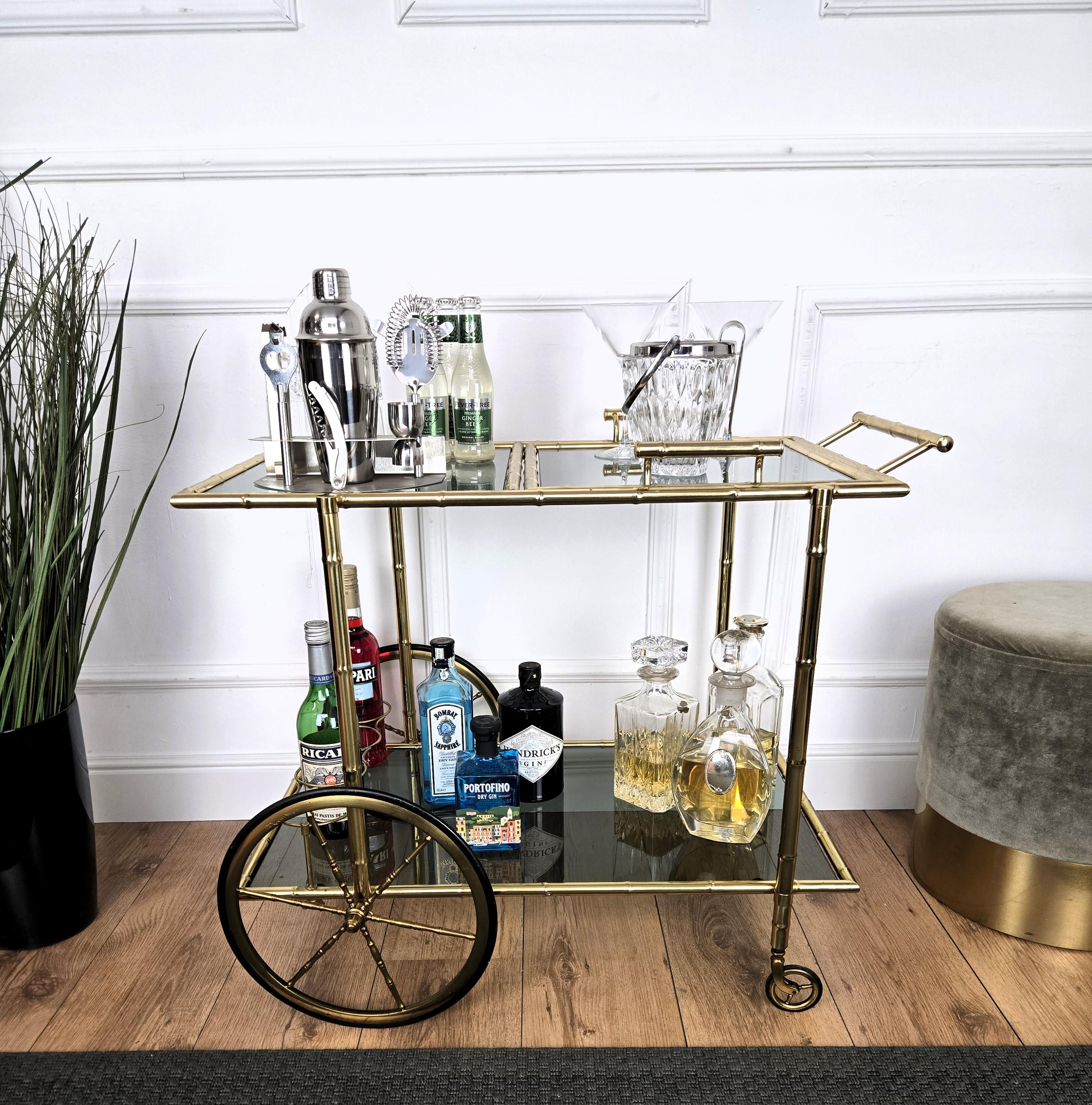 Magnifique et élégant chariot de bar italien vintage des années 1970 à deux niveaux en faux bambou, laiton et verre, avec de superbes roues en laiton, des plateaux en verre fumé vert et un plateau amovible. Très bon état avec laiton doré brillant.